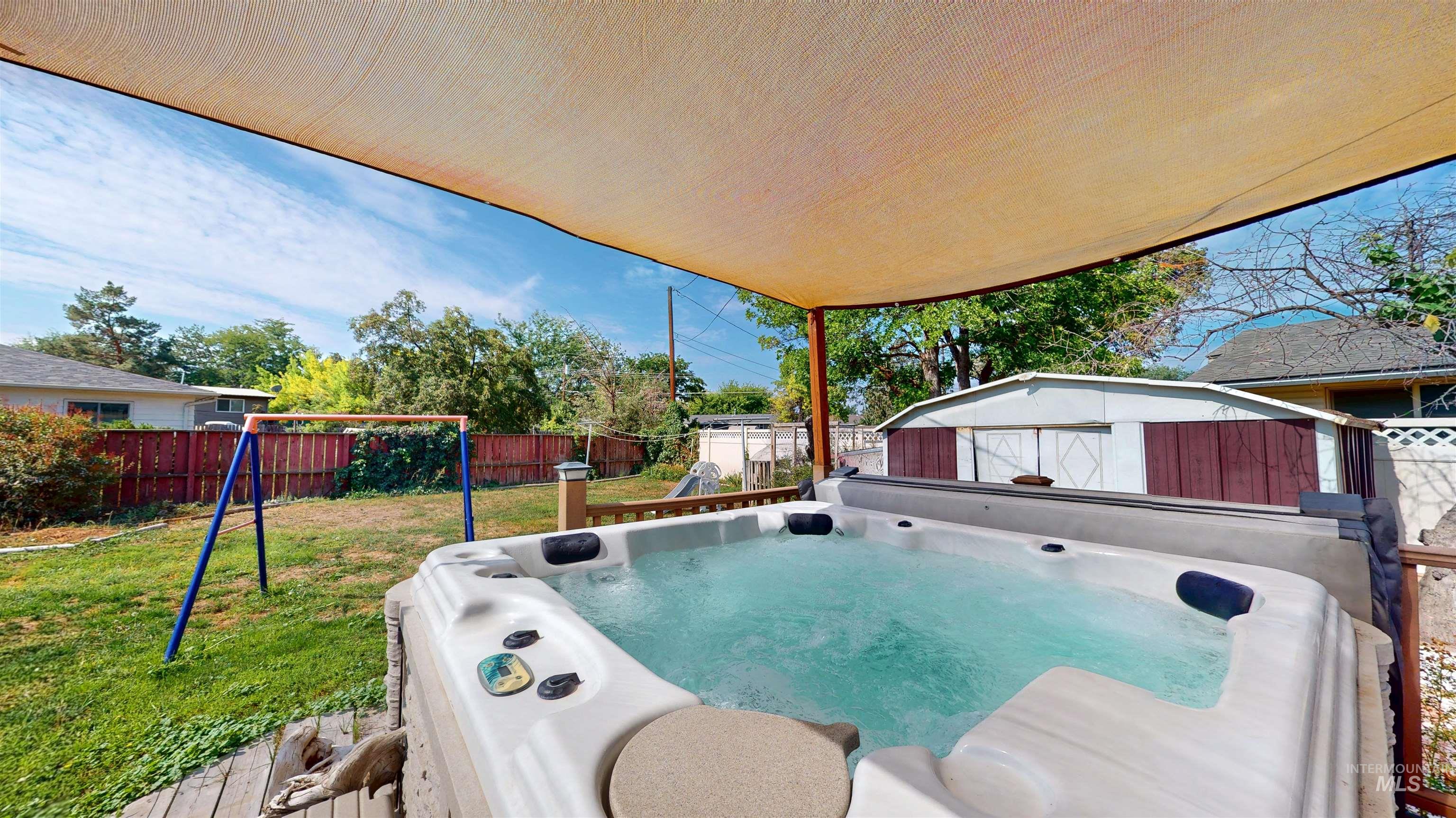 View of swimming pool with a hot tub, a fenced backyard, and a shed