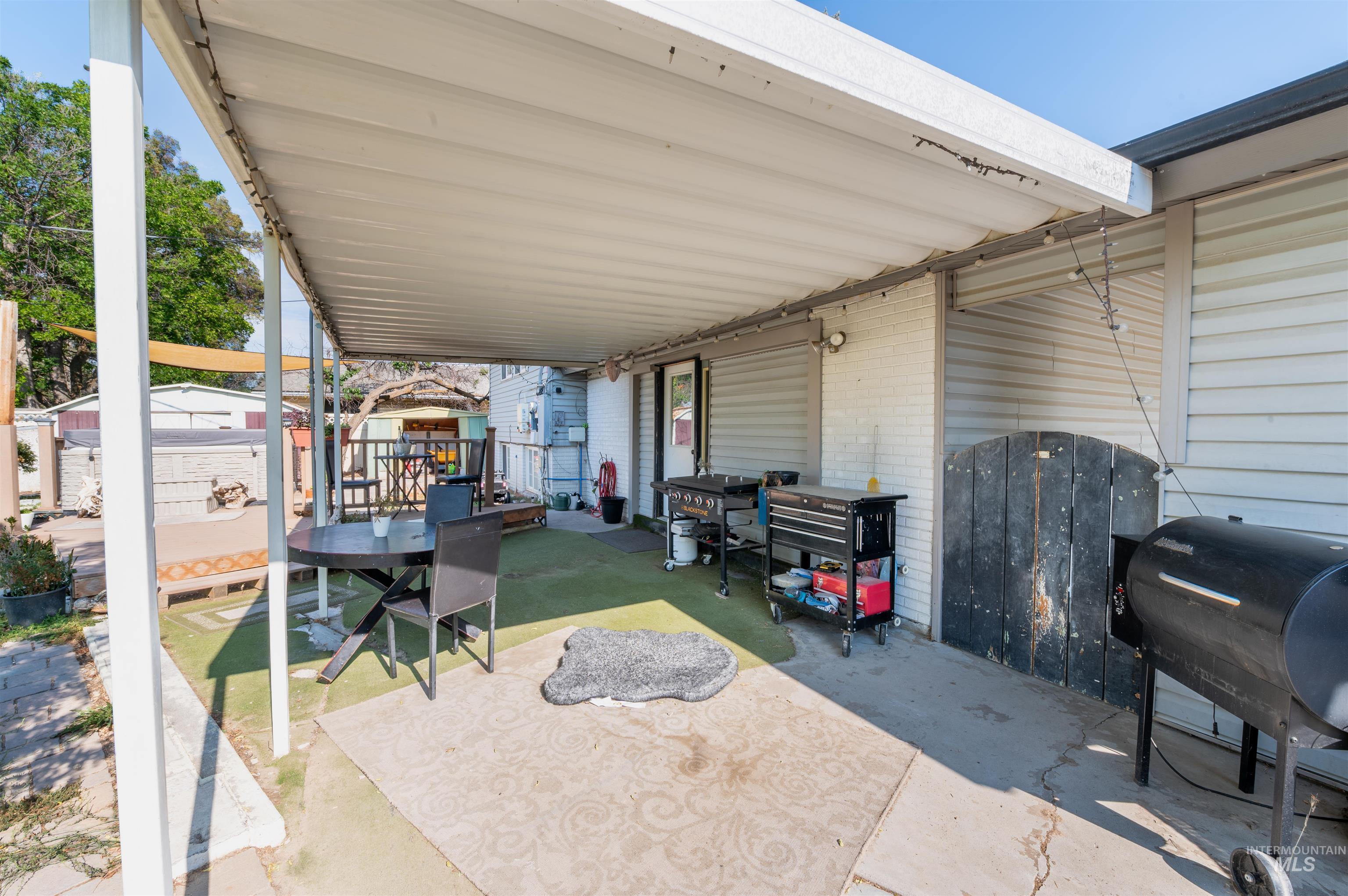 View of patio with area for grilling, outdoor dining space, and an outdoor structure