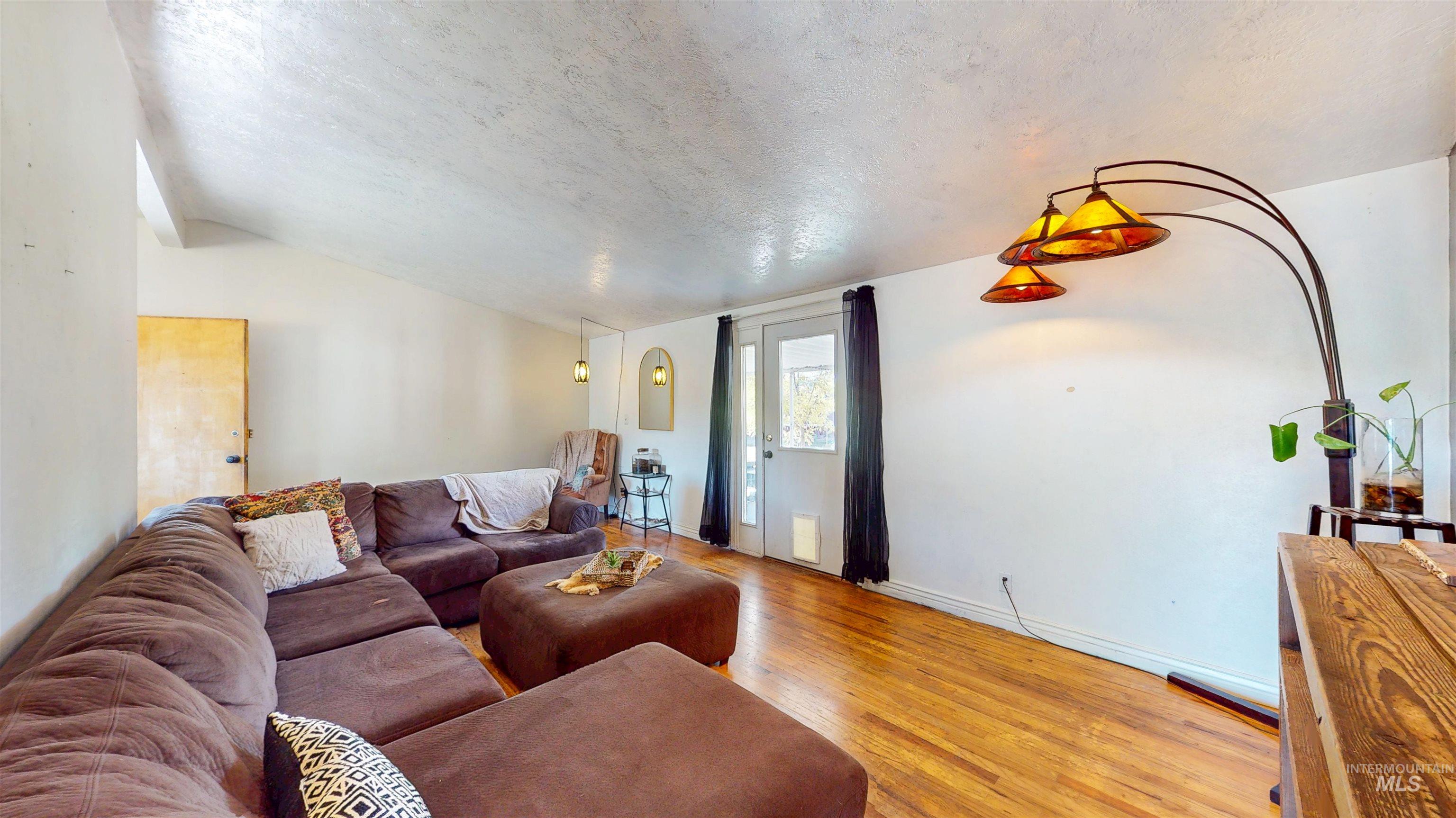 Living area featuring a textured ceiling, light wood finished floors, and lofted ceiling