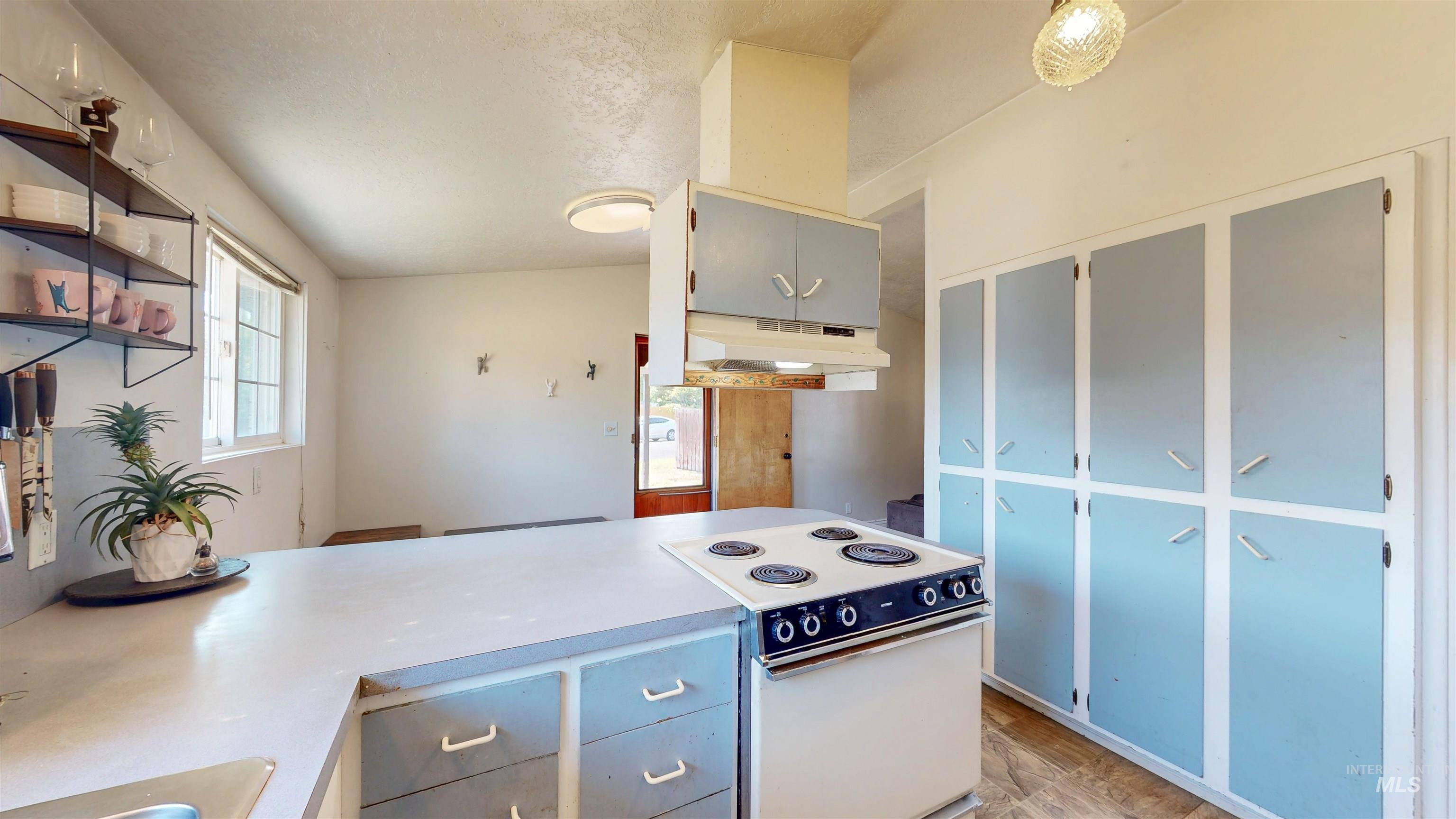 Kitchen featuring white electric range oven, open shelves, a peninsula, under cabinet range hood, and light countertops