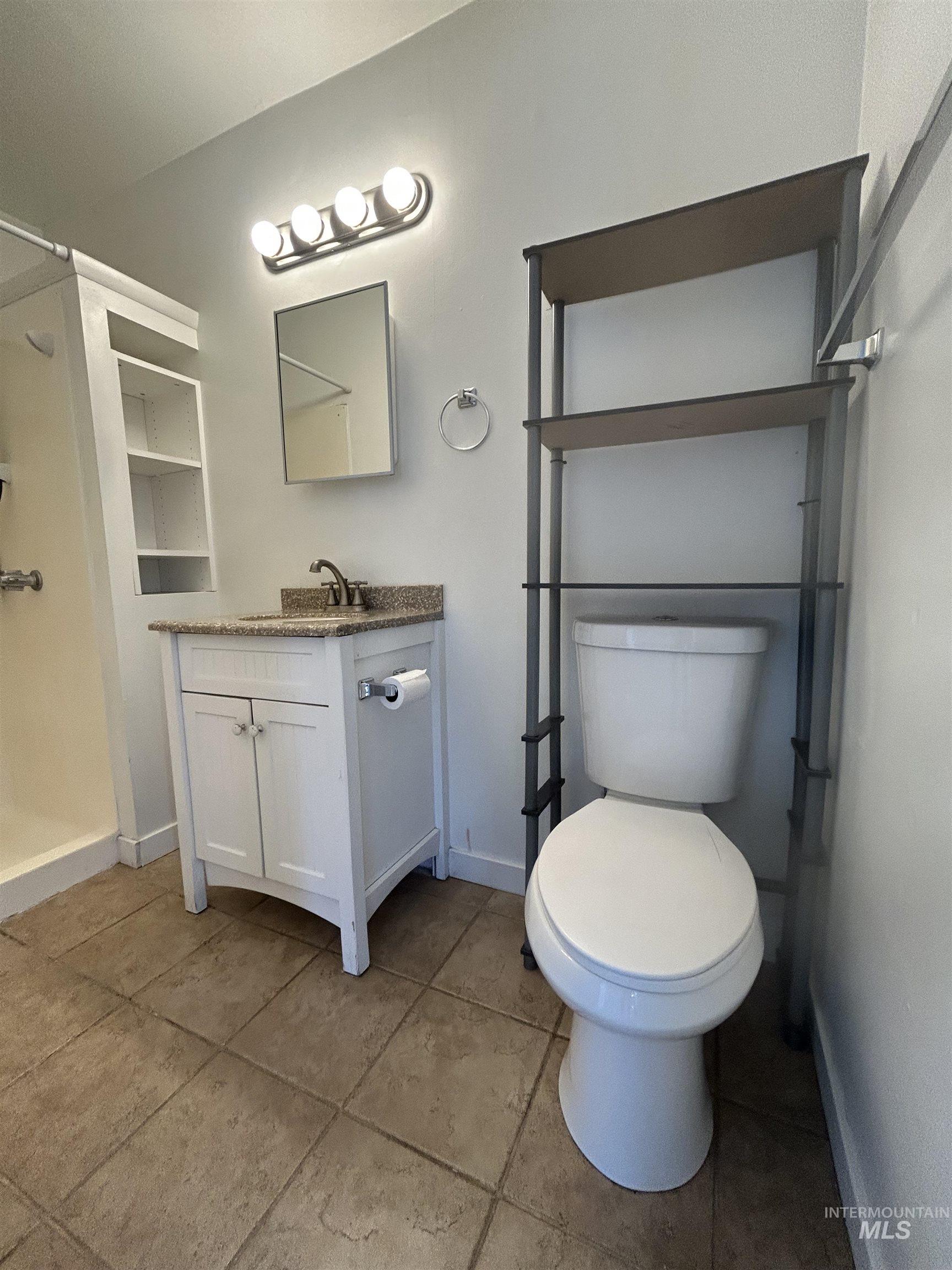 Full bathroom with vanity, light tile patterned floors, and a stall shower