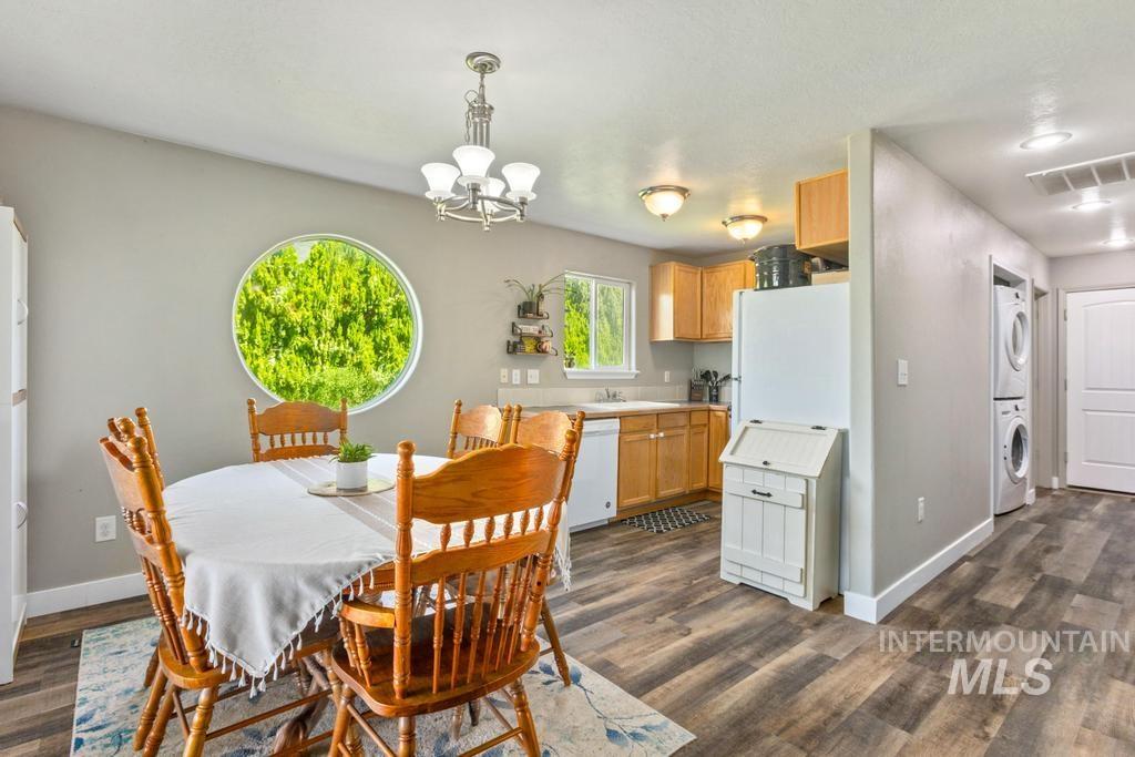 Dining area featuring stacked washer and clothes dryer, a chandelier, and dark wood finished floors