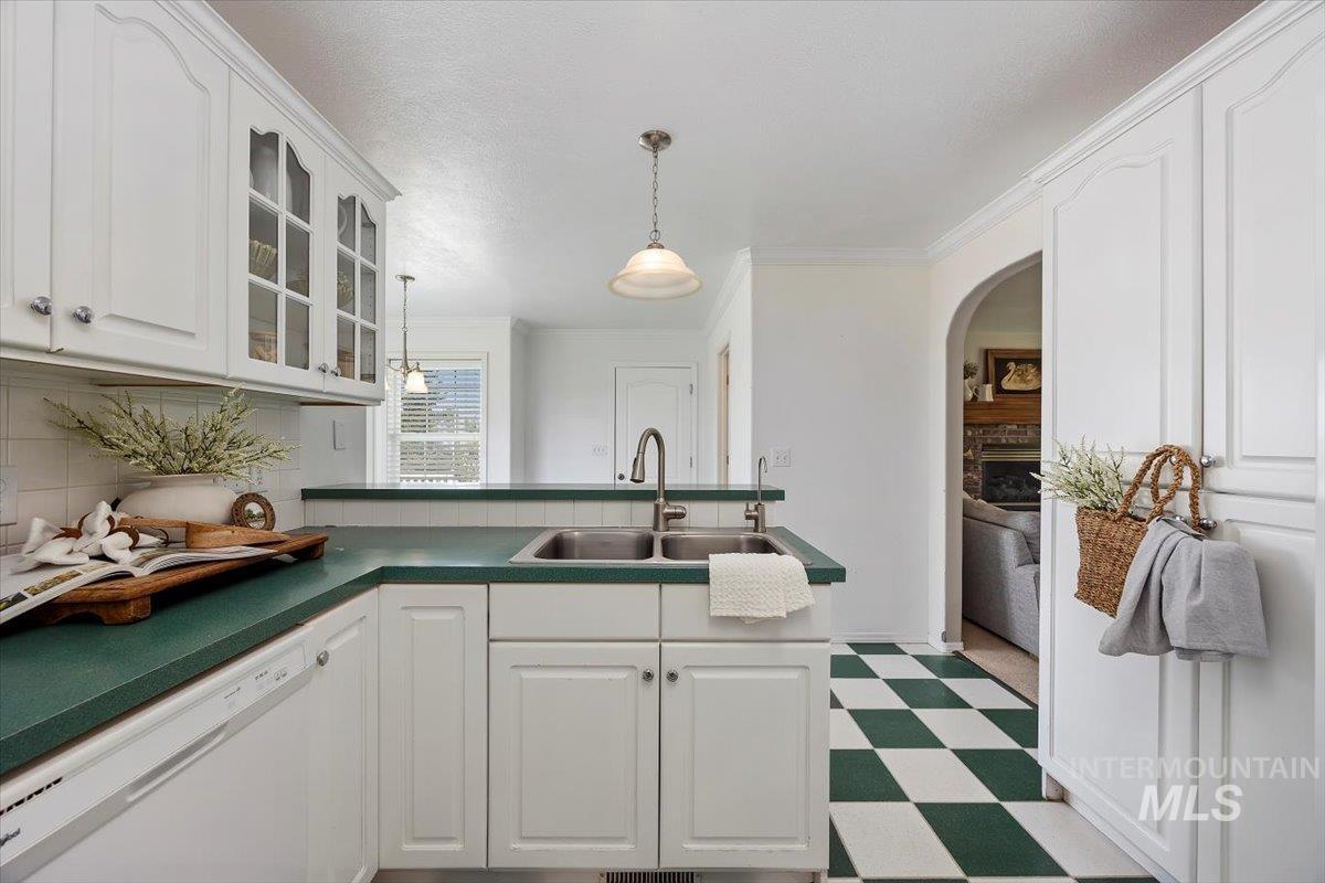Kitchen with dishwasher, white cabinets, dark floors, glass insert cabinets, and dark countertops