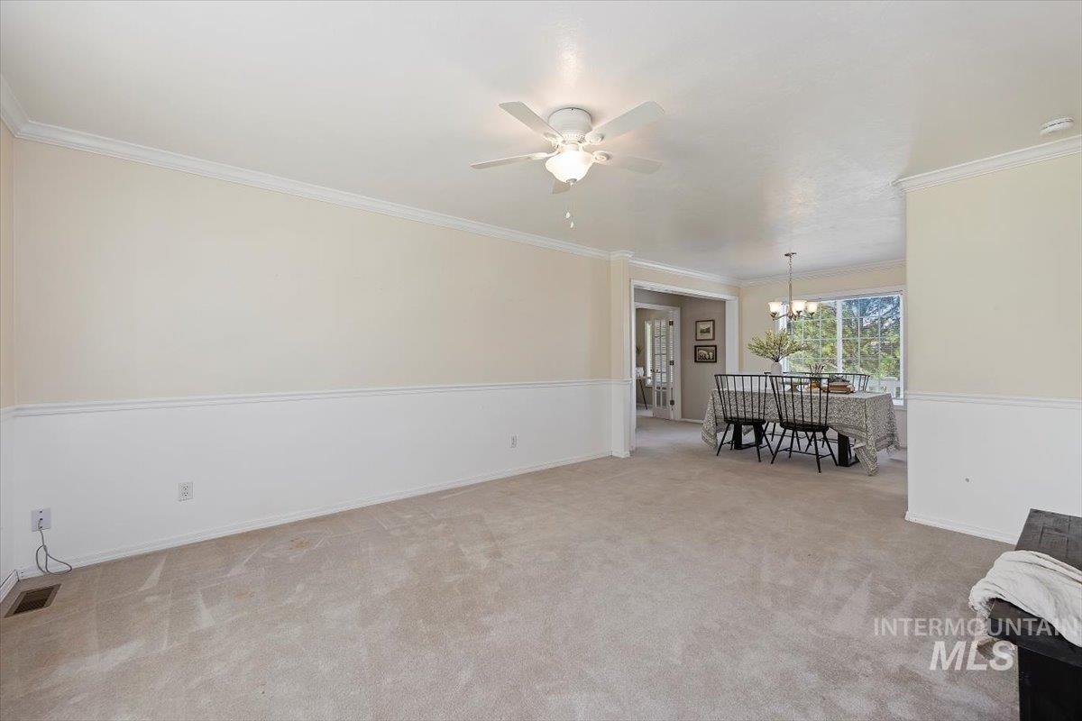 Living area featuring crown molding, light colored carpet, a ceiling fan, and a chandelier