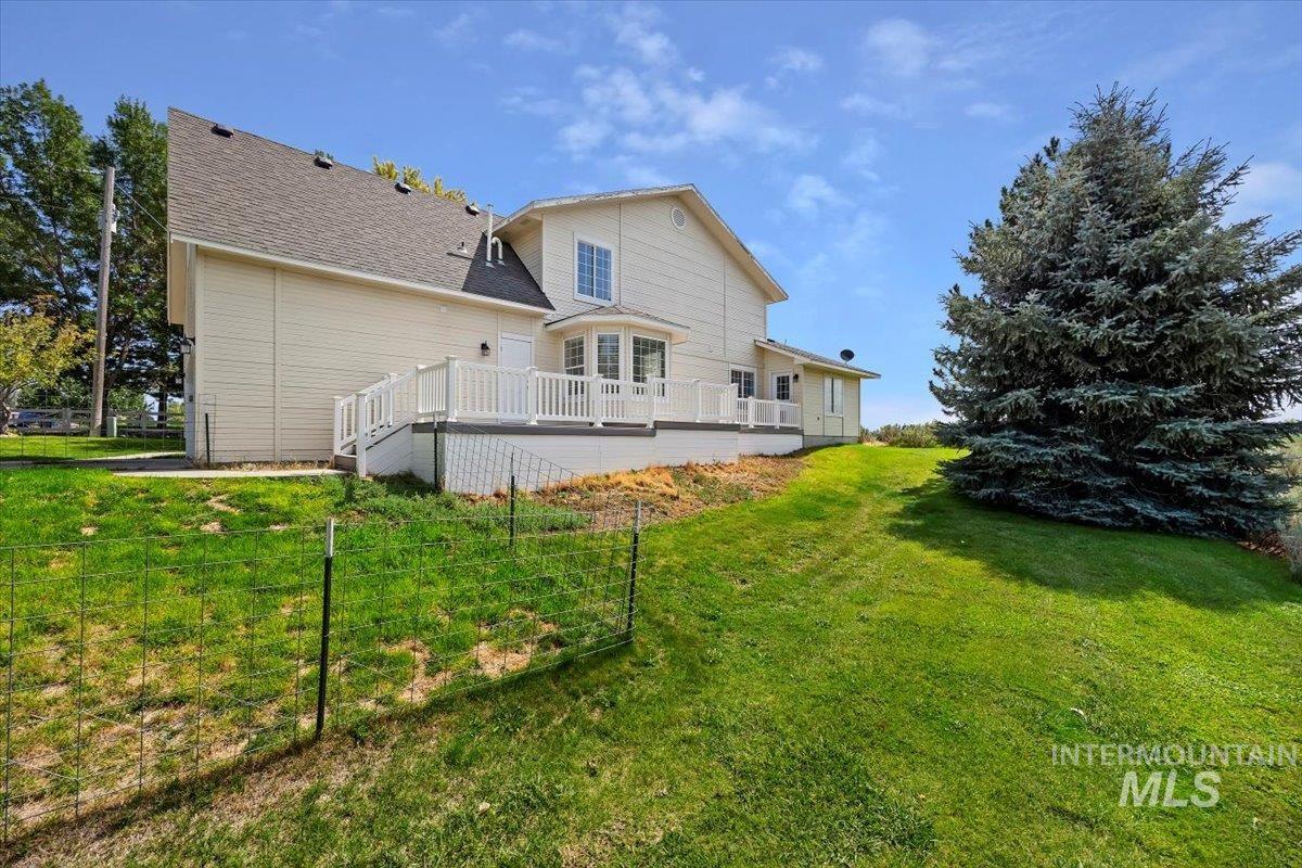 Rear view of property with a deck, a lawn, and a shingled roof