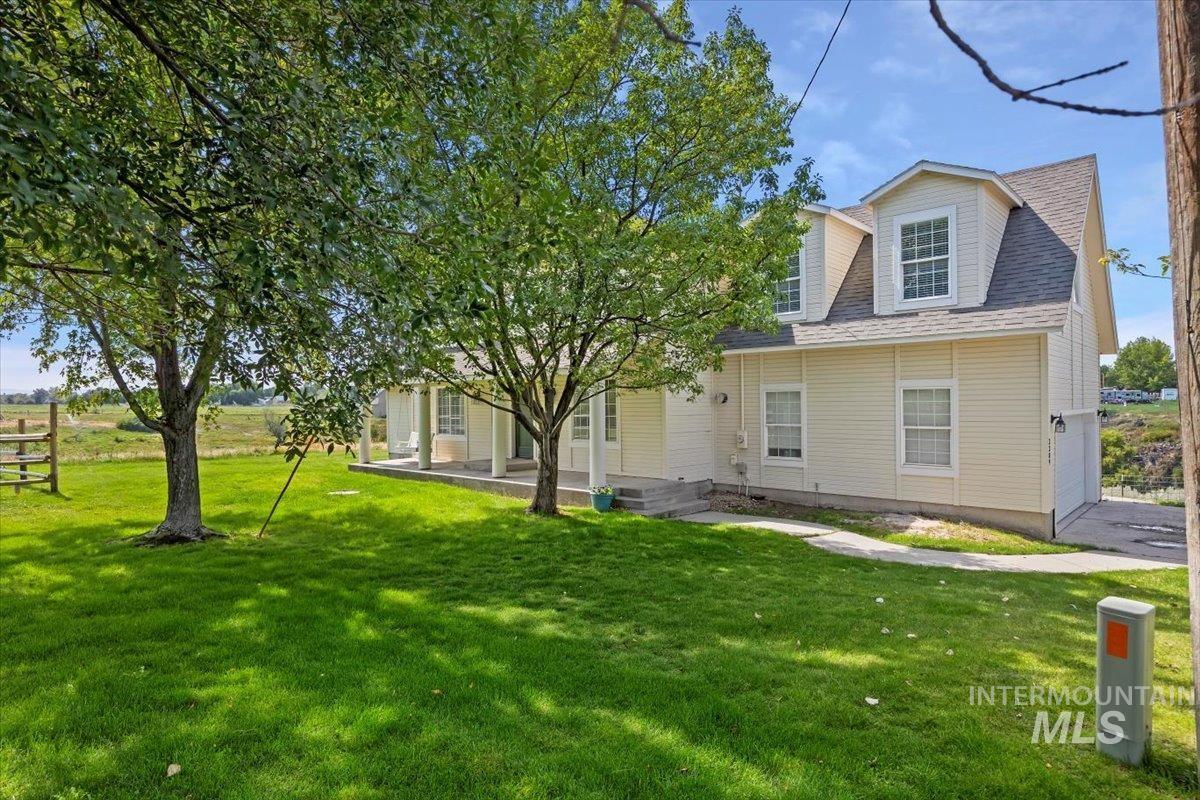 View of front of property featuring a front lawn, roof with shingles, and a garage