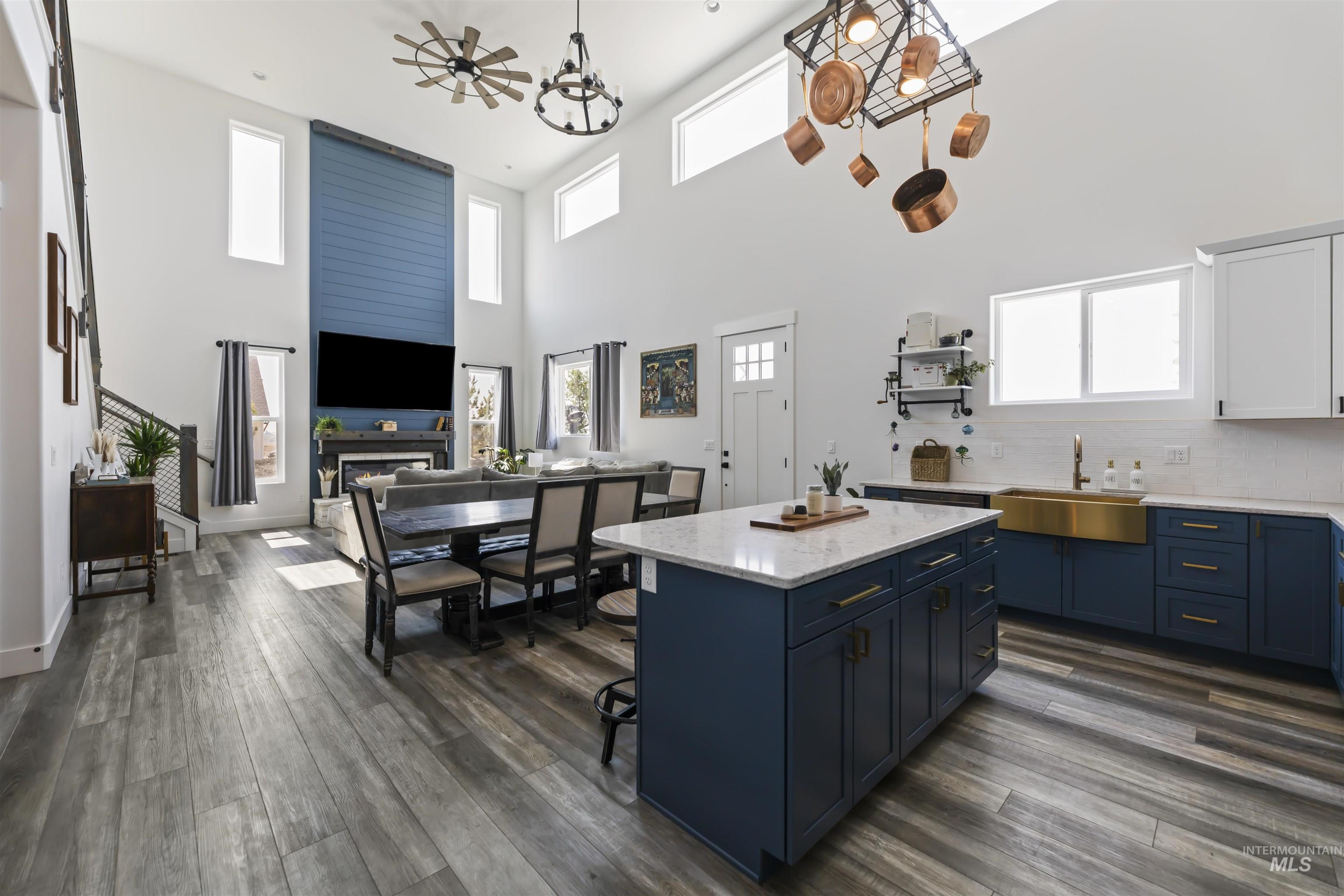 Kitchen with blue cabinets, tasteful backsplash, light stone countertops, a high ceiling, and dark wood-type flooring