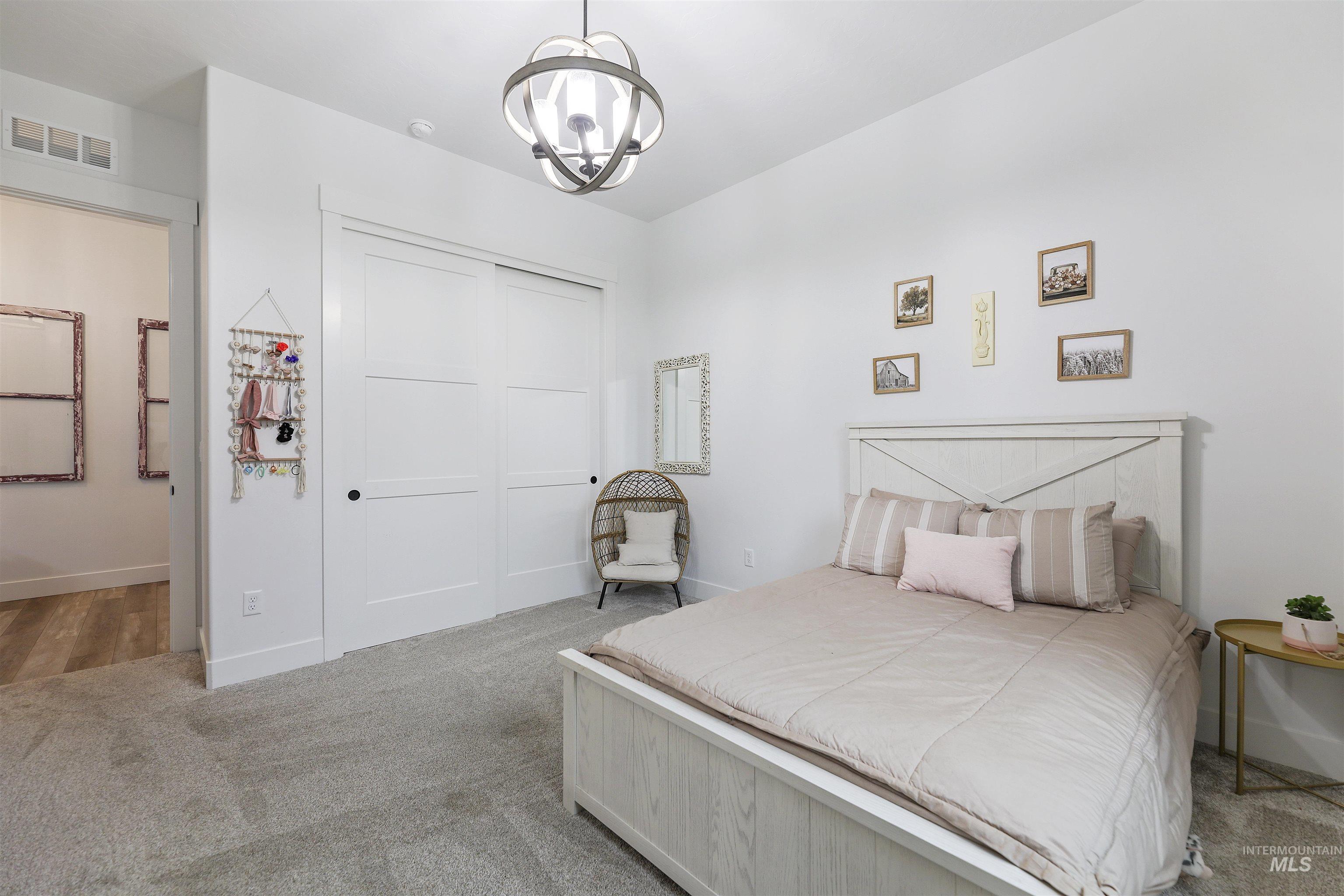 Carpeted bedroom featuring a closet and a chandelier