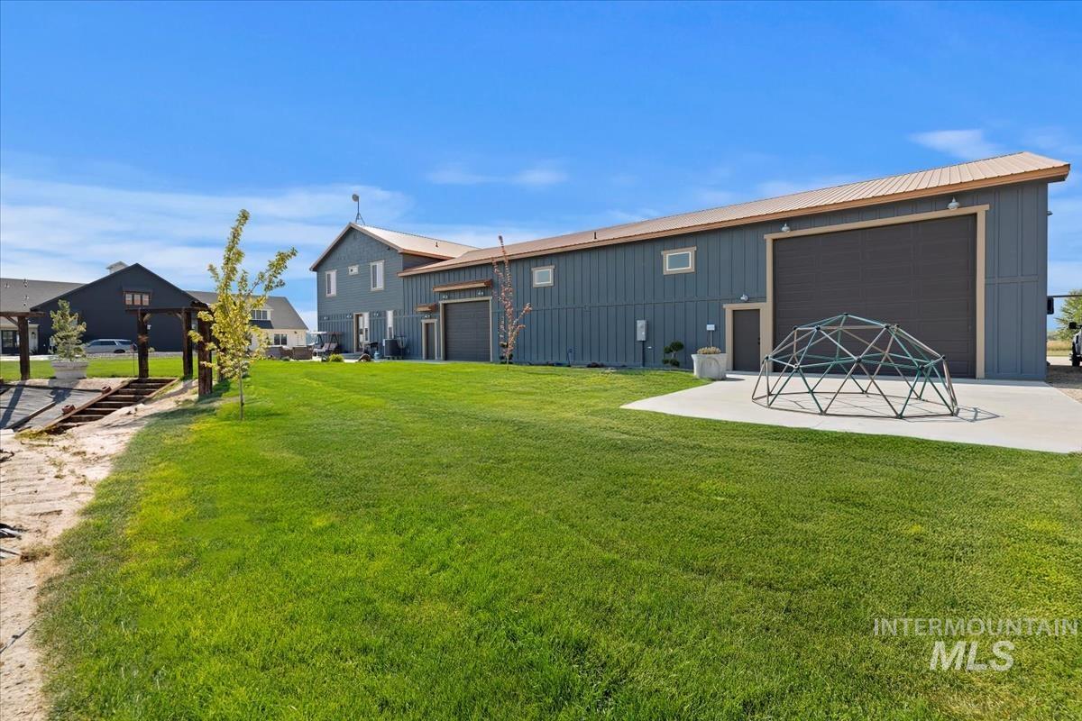 Rear view of property with board and batten siding, a lawn, a metal roof, and a garage