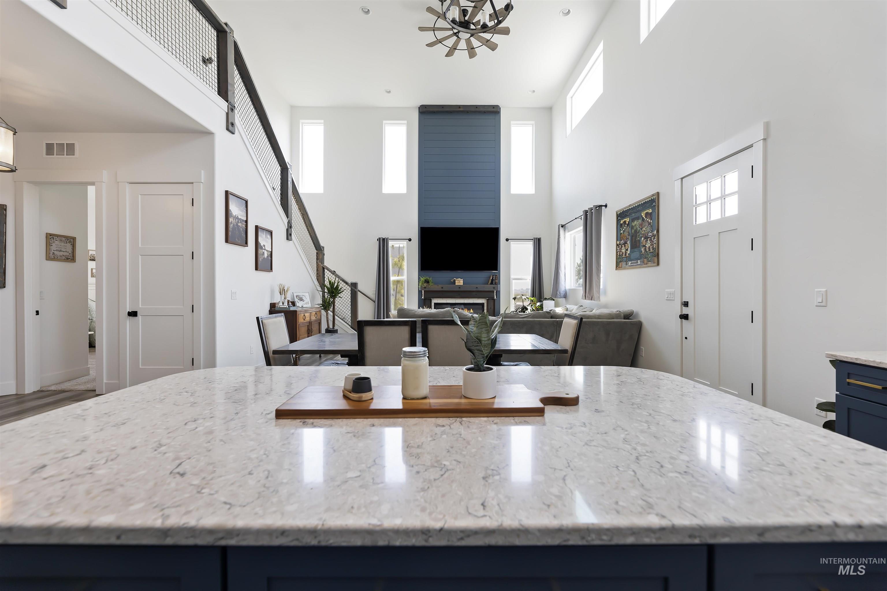 Kitchen featuring blue cabinets, light stone counters, open floor plan, a high ceiling, and a center island