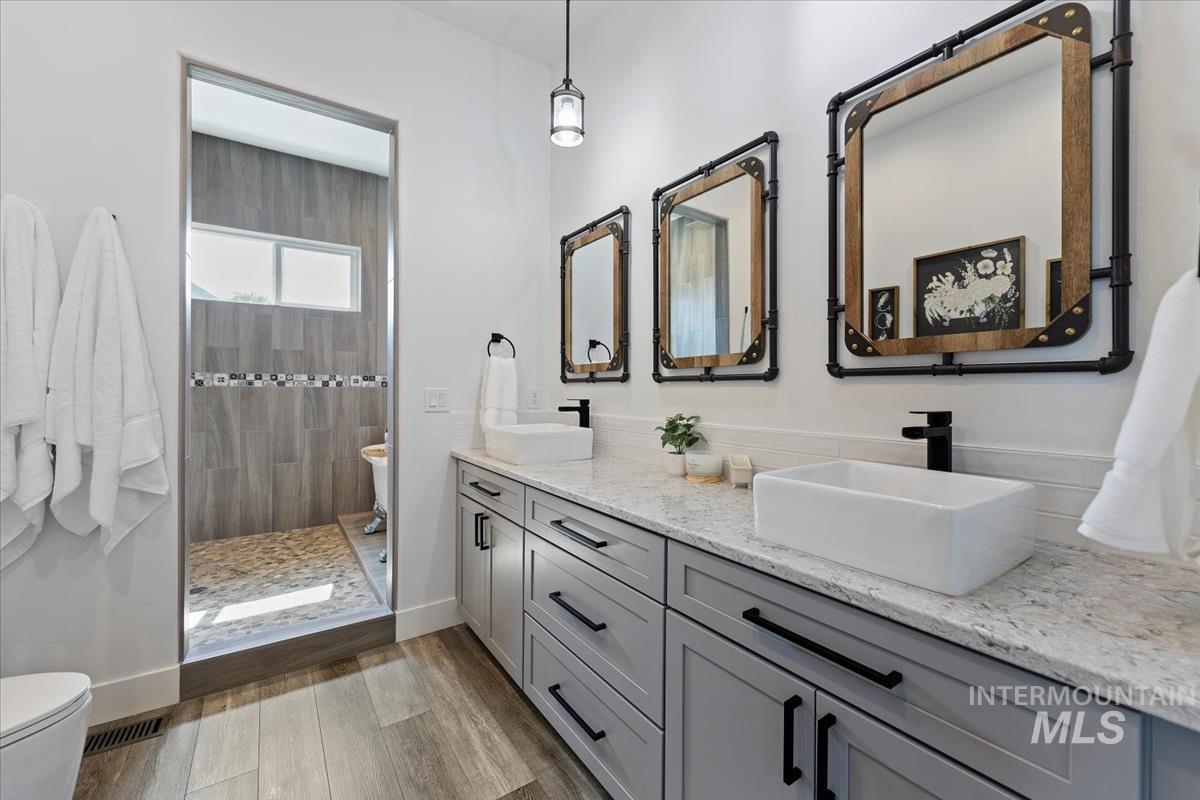 Full bathroom with double vanity, light wood-style floors, and walk in shower