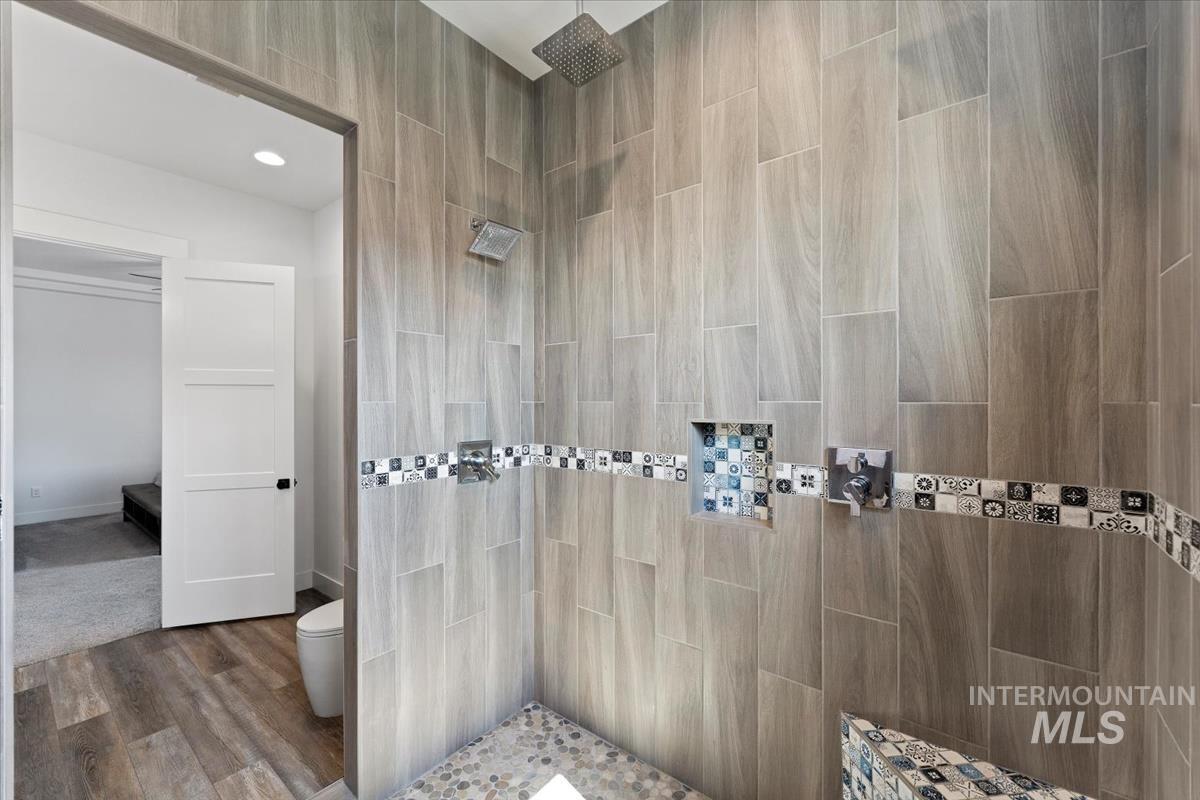 Bathroom with tiled shower, dark wood-type flooring, and recessed lighting