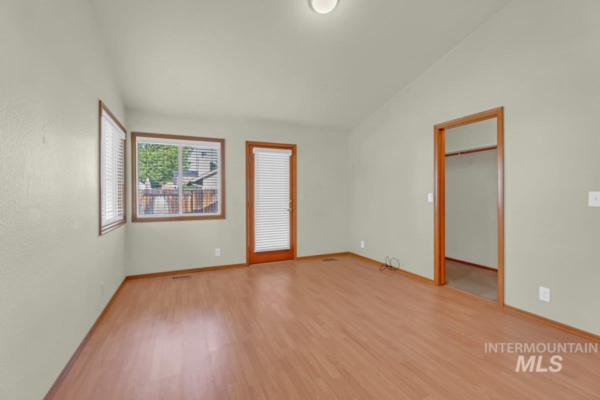 Unfurnished room featuring light wood-style flooring and lofted ceiling