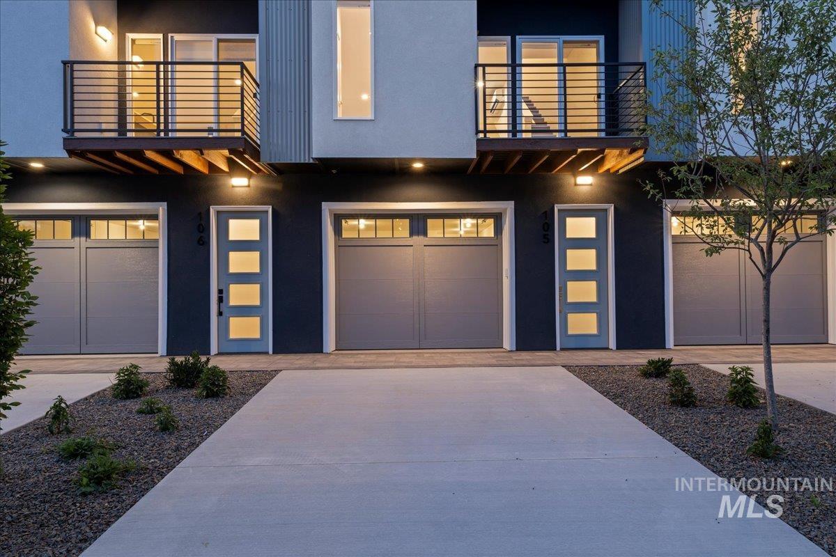 Contemporary home featuring a garage, a balcony, driveway, and stucco siding