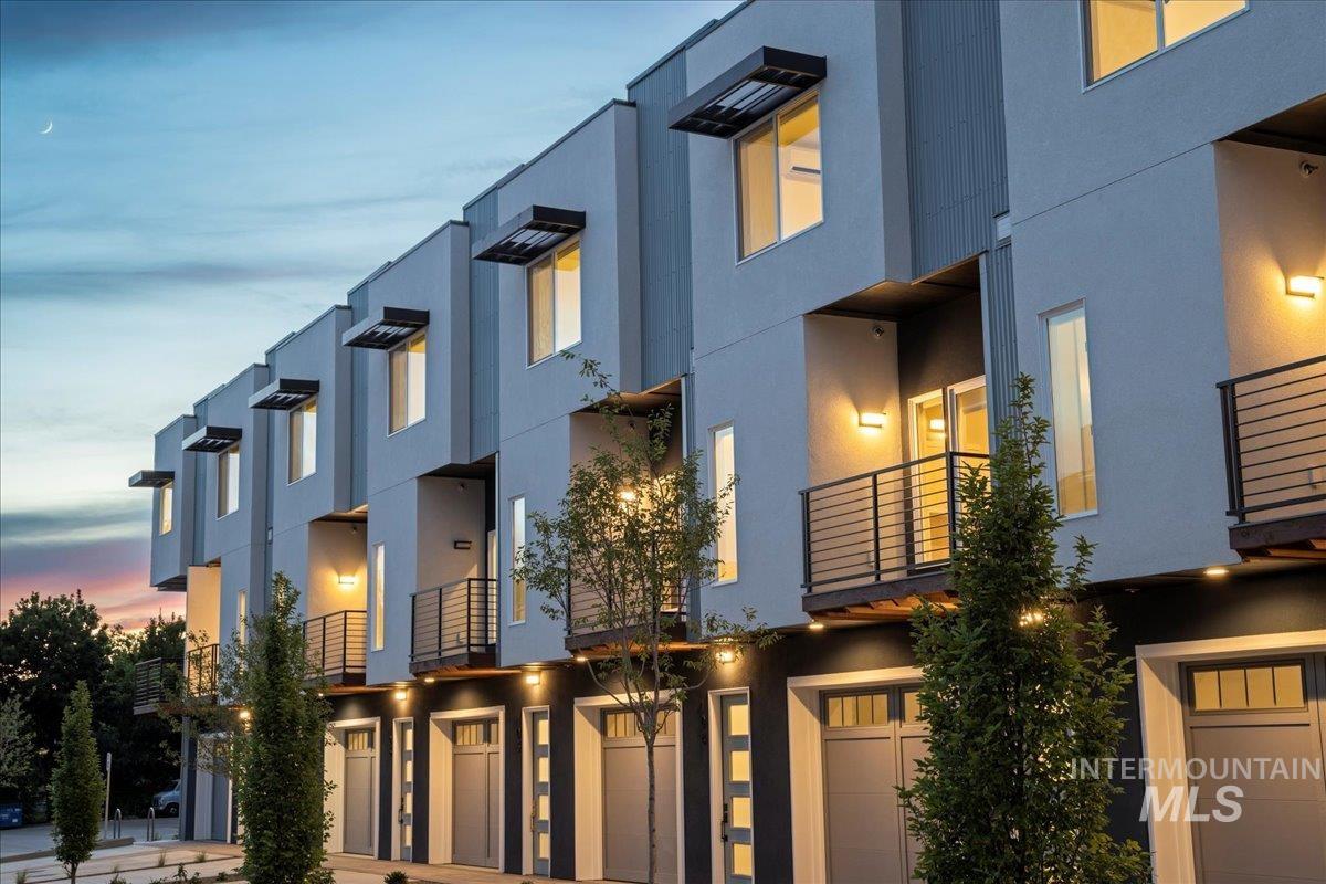 Modern home with a balcony, an attached garage, and stucco siding