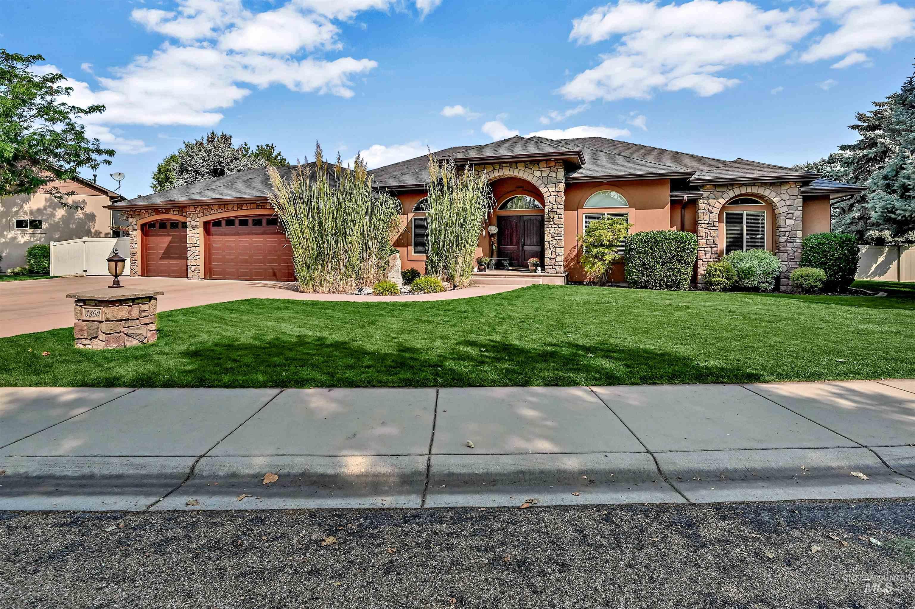 View of front of house featuring stone siding, driveway, a garage, and stucco siding