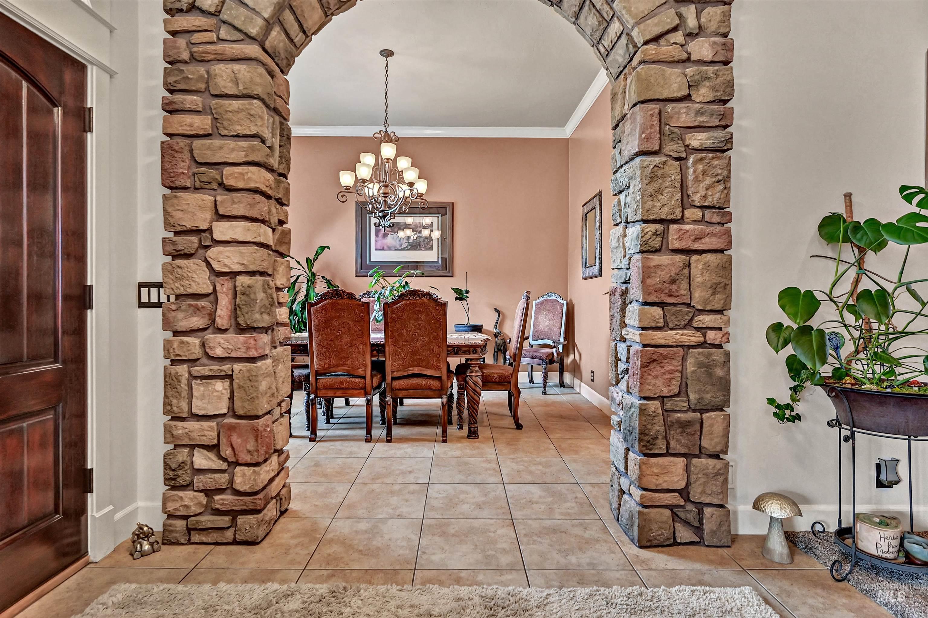 Dining room with ornamental molding, light tile patterned floors, arched walkways, and a chandelier