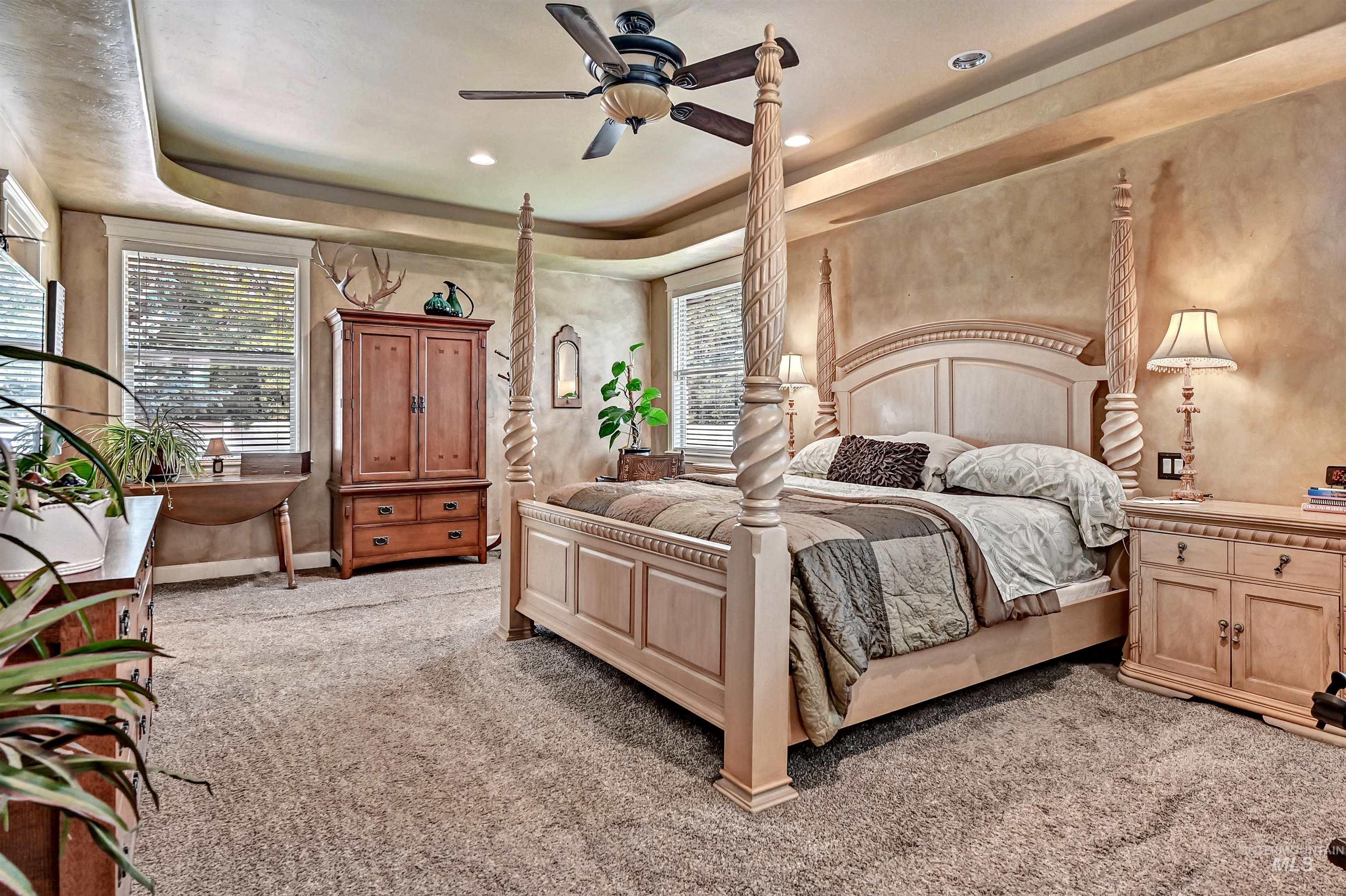 Bedroom with a tray ceiling, light colored carpet, a ceiling fan, and recessed lighting