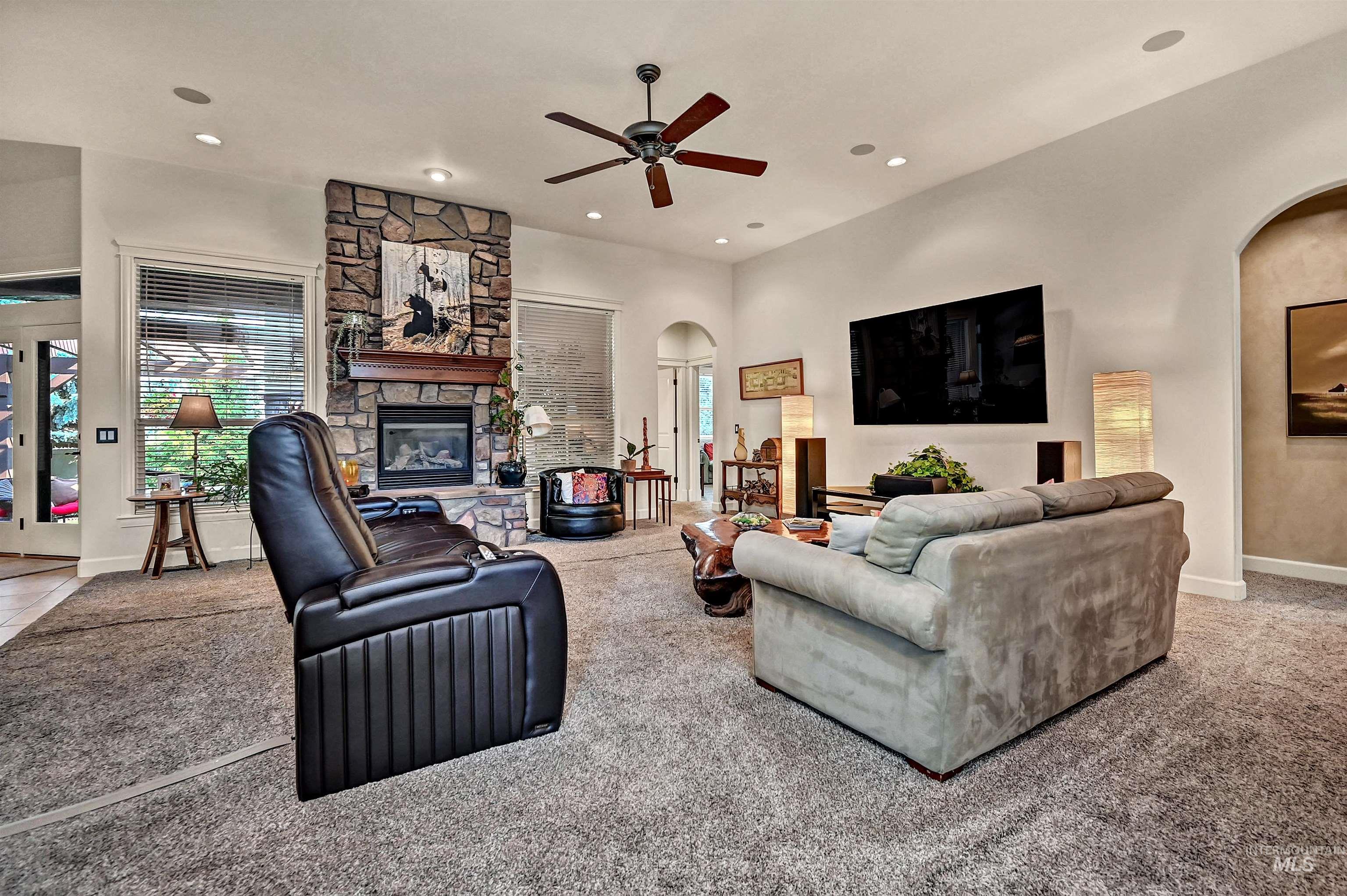 Living room featuring arched walkways, light carpet, recessed lighting, a fireplace, and ceiling fan