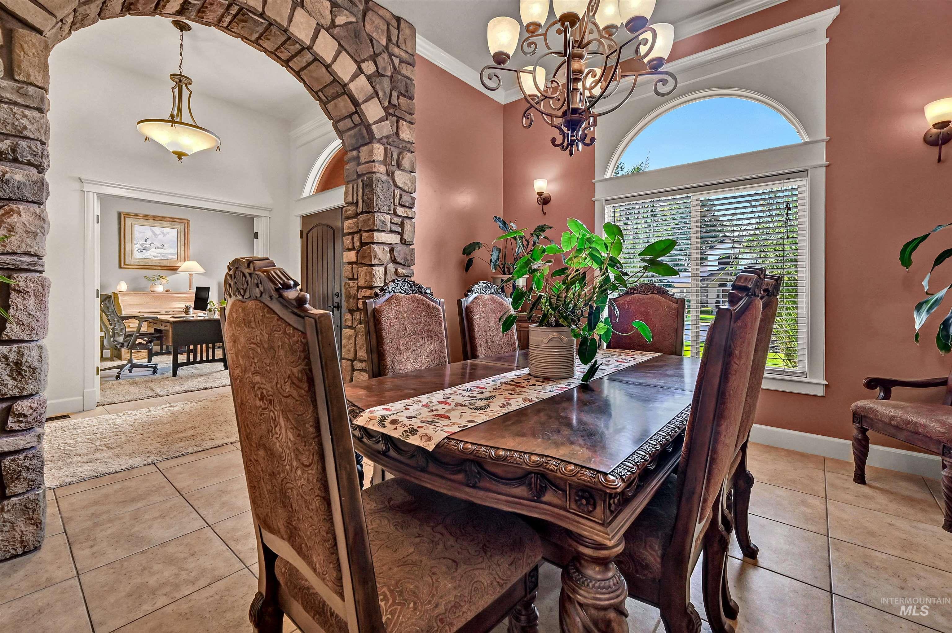 Dining room featuring arched walkways, light tile patterned flooring, ornamental molding, and a chandelier