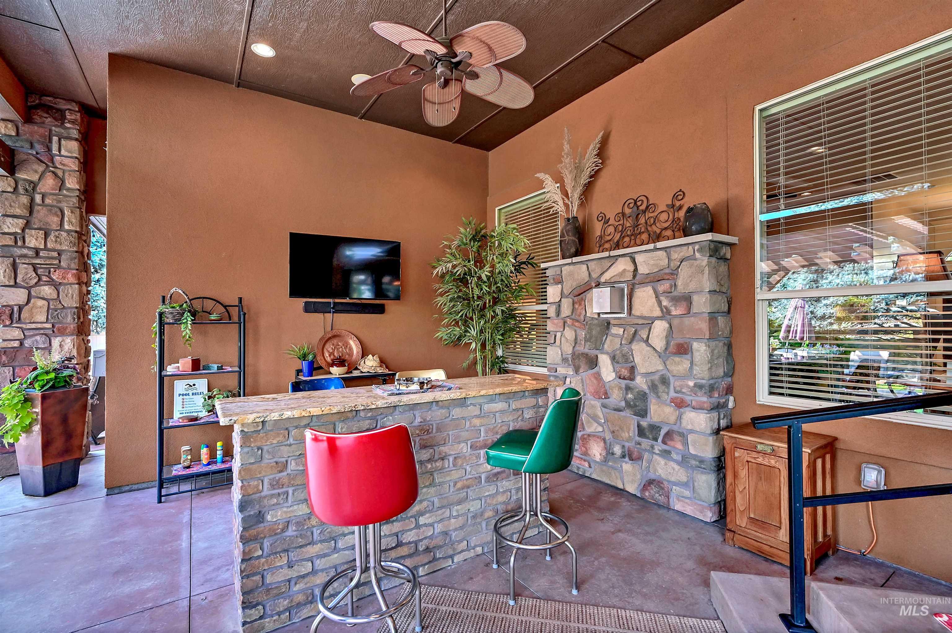 Indoor dry bar featuring a ceiling fan and light countertops