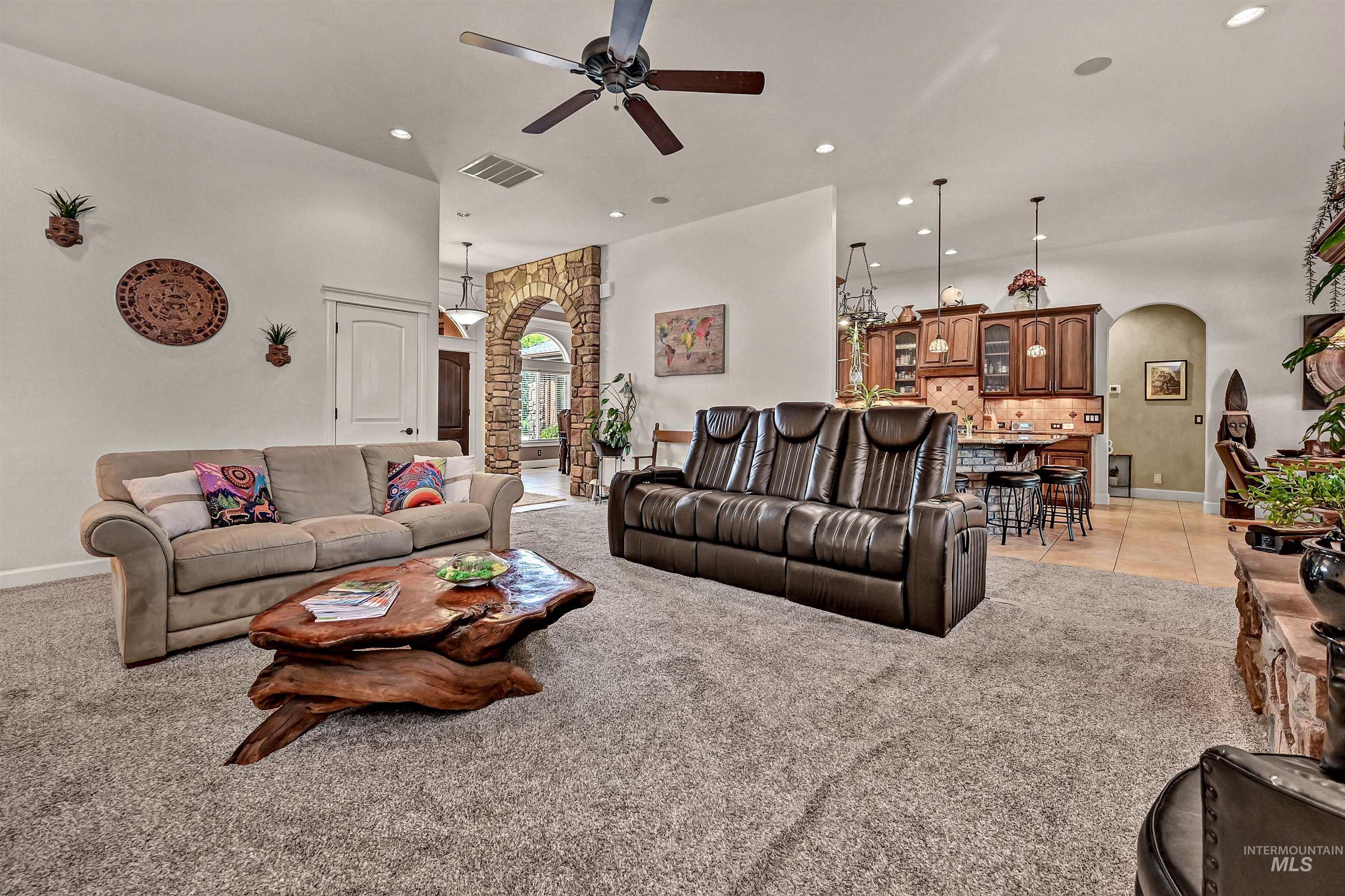 Living area with arched walkways, light carpet, ceiling fan, and recessed lighting