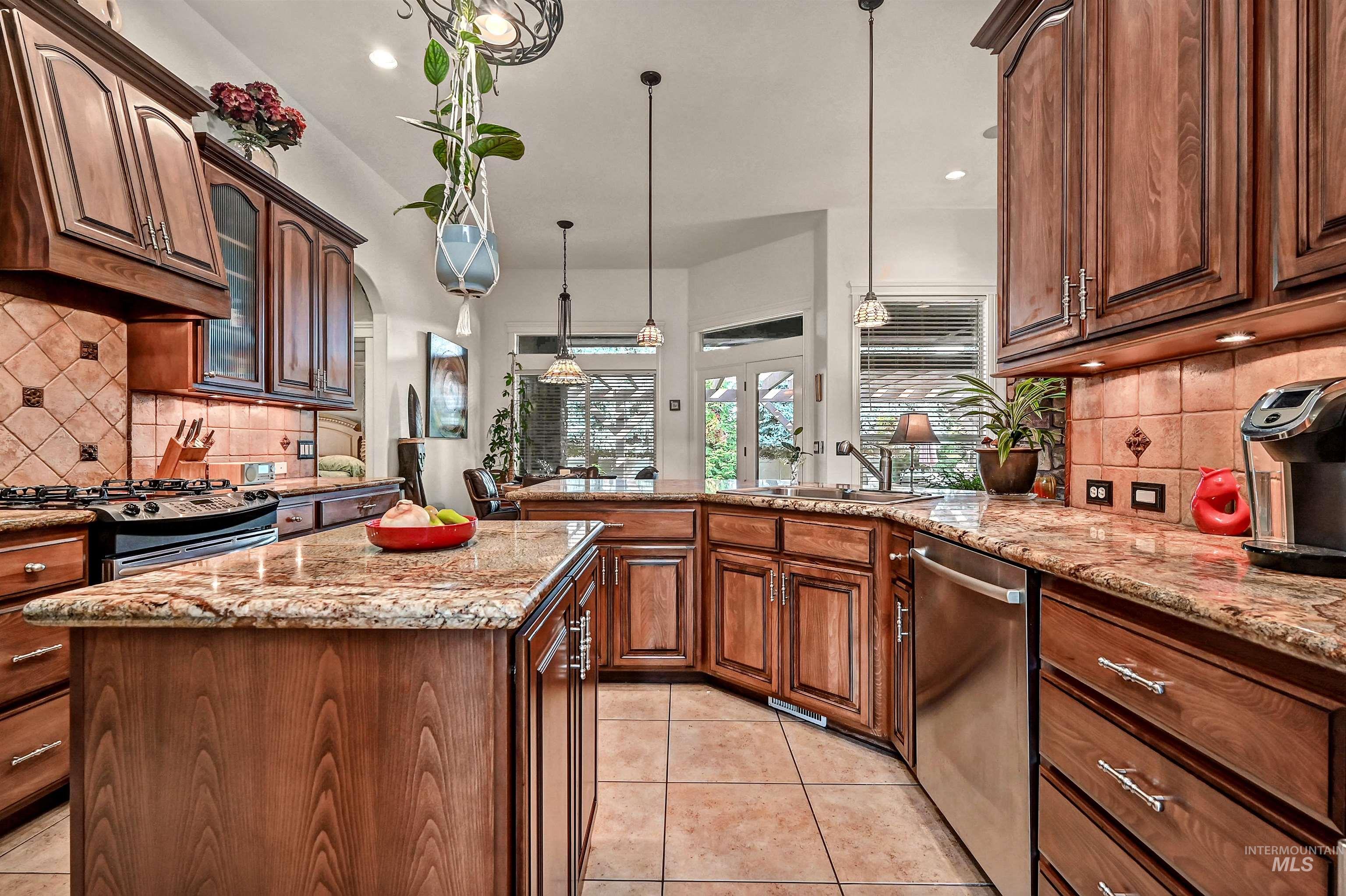 Kitchen featuring backsplash, hanging light fixtures, light tile patterned floors, light stone counters, and recessed lighting