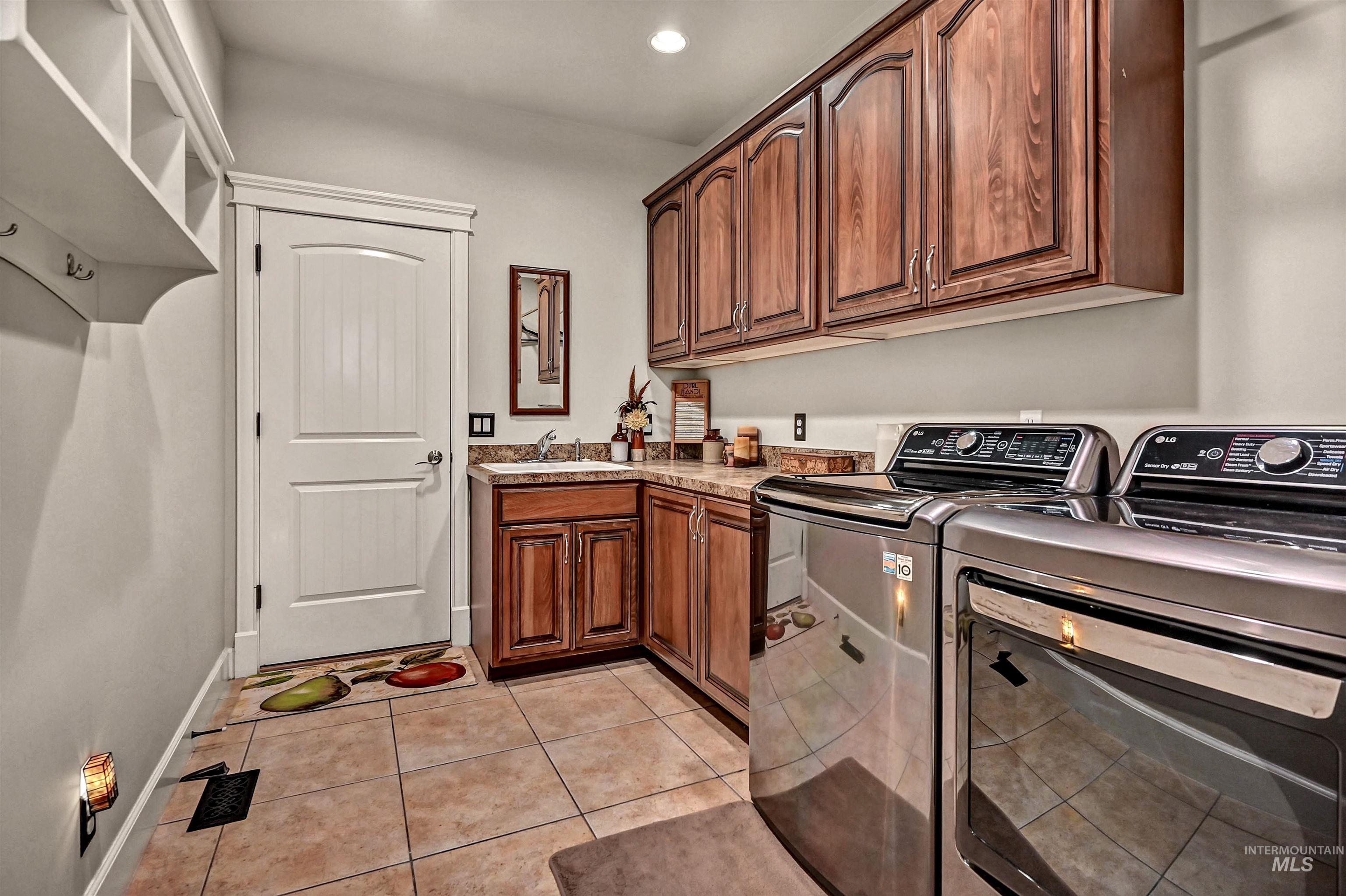 Laundry area featuring light tile patterned floors, washer and clothes dryer, recessed lighting, and cabinet space