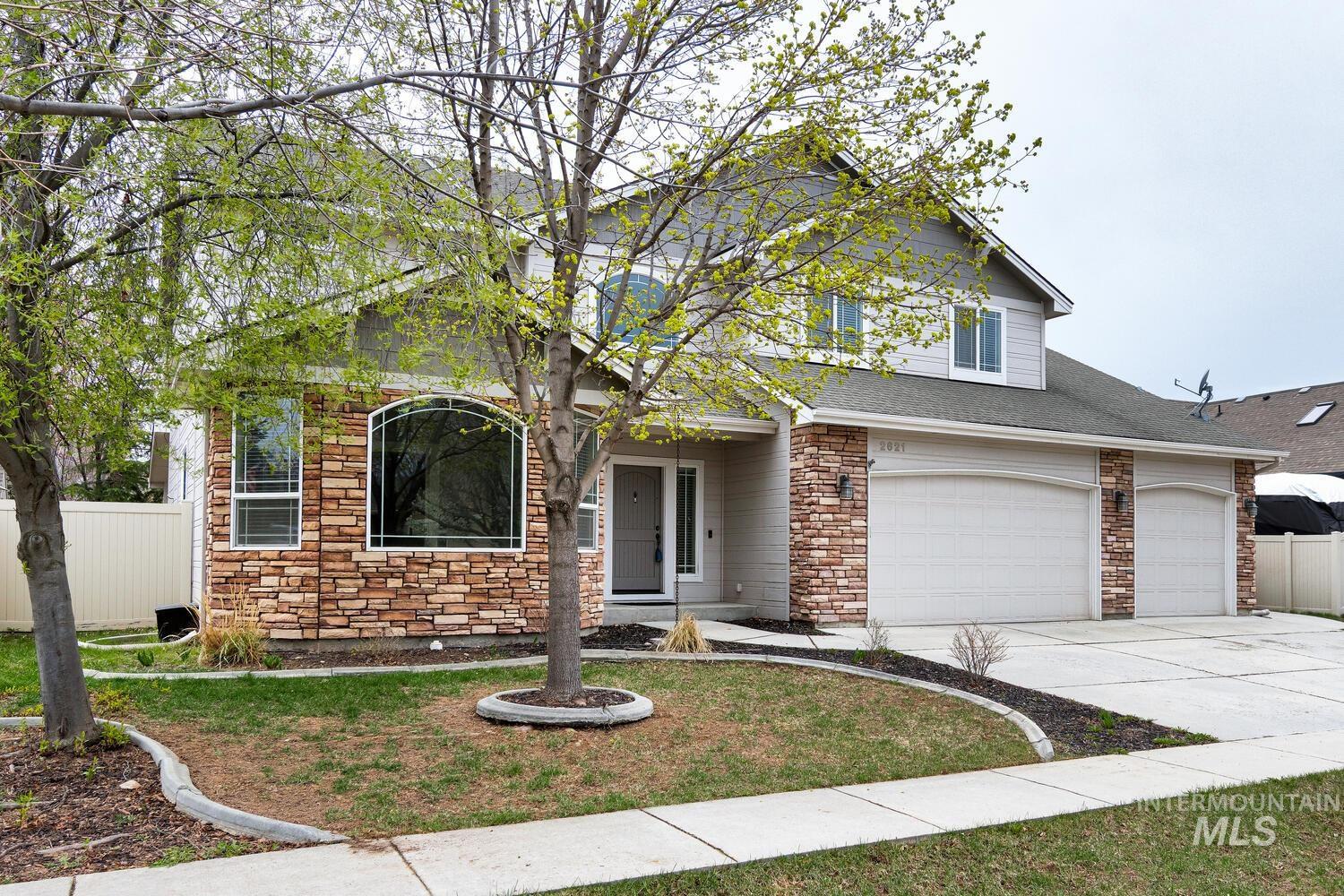 View of front of house featuring stone siding, driveway, a garage, and roof with shingles