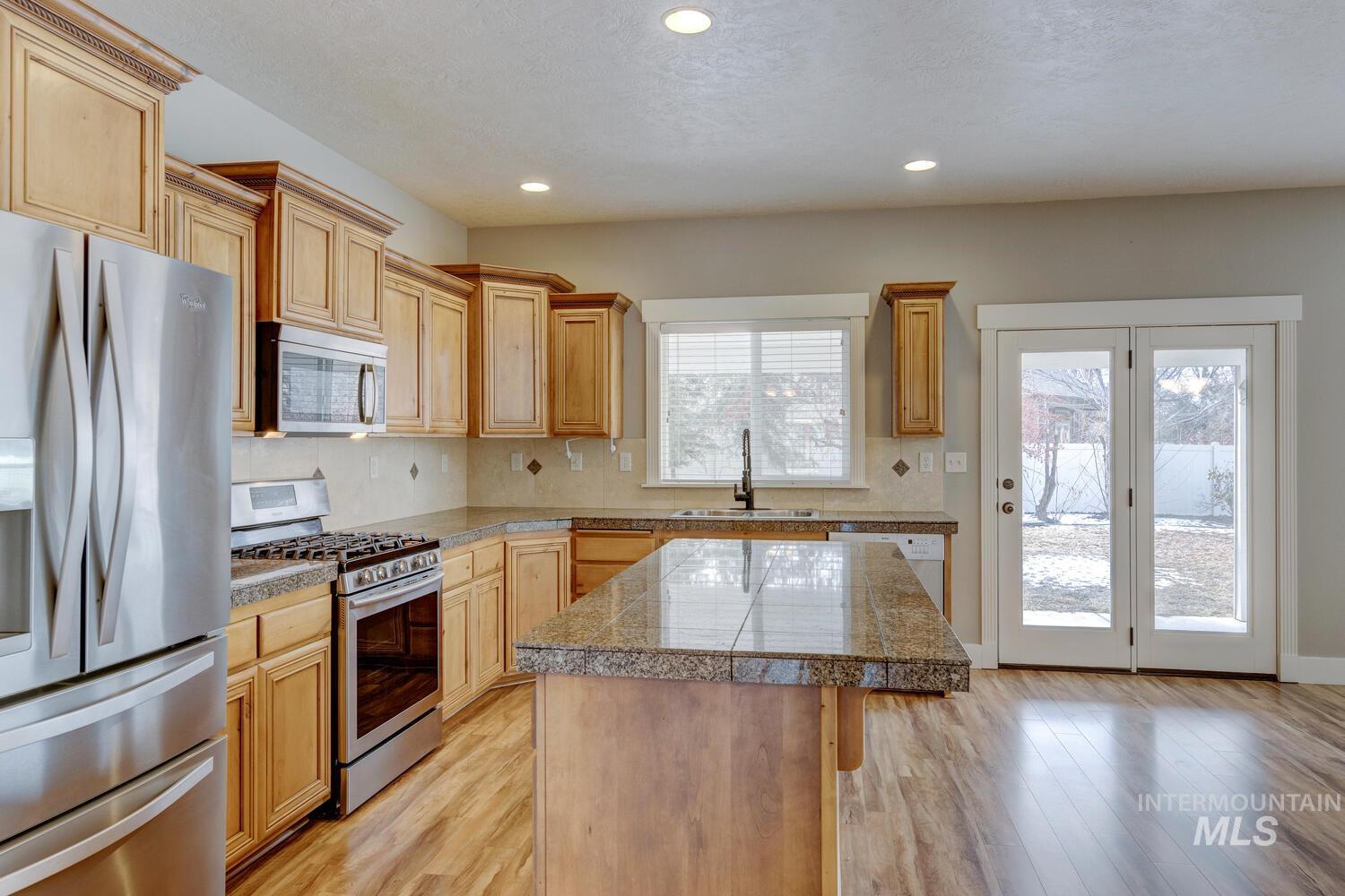 Kitchen featuring tile countertops, stainless steel appliances, a center island, decorative backsplash, and recessed lighting