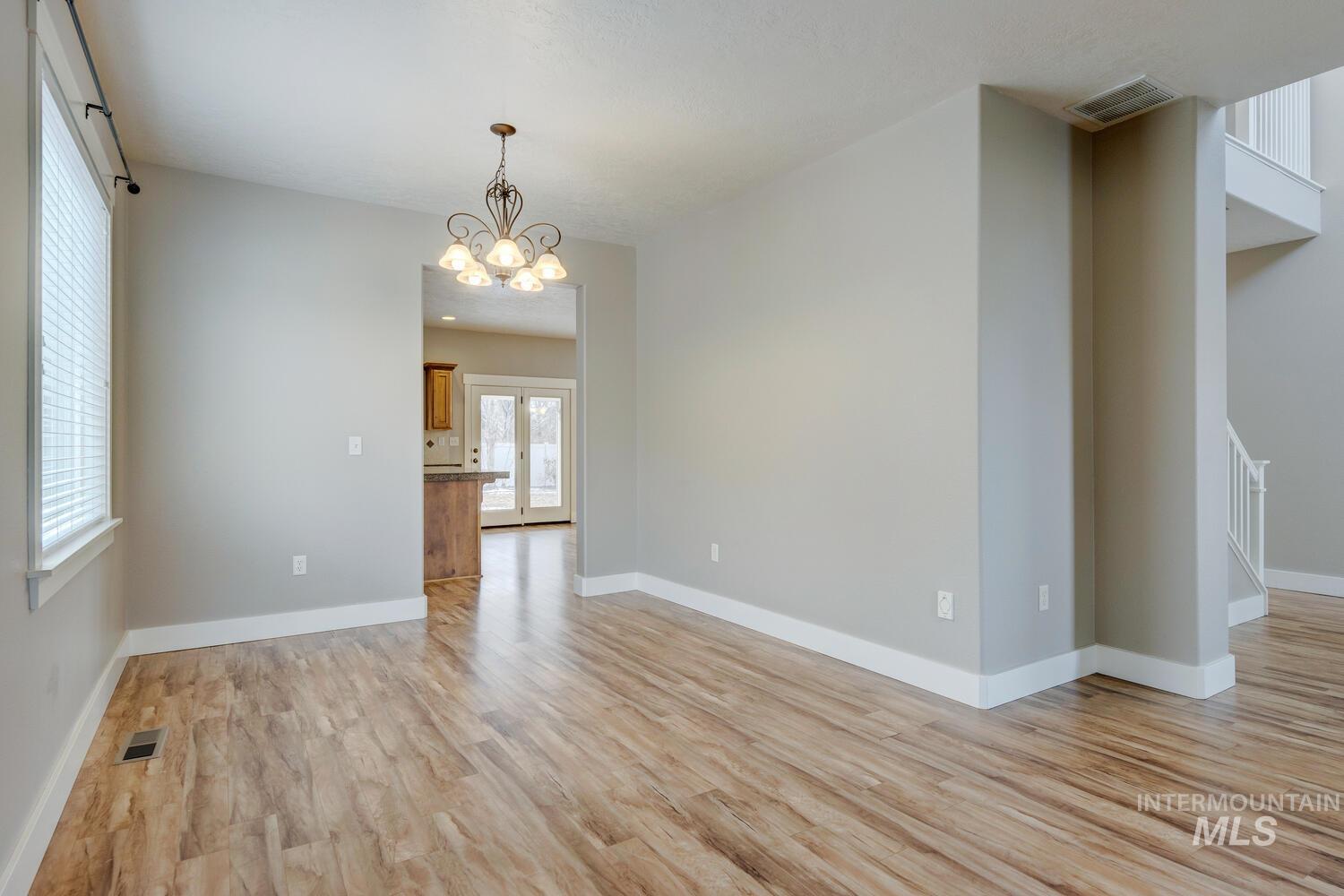 Unfurnished living room with light wood finished floors and a chandelier