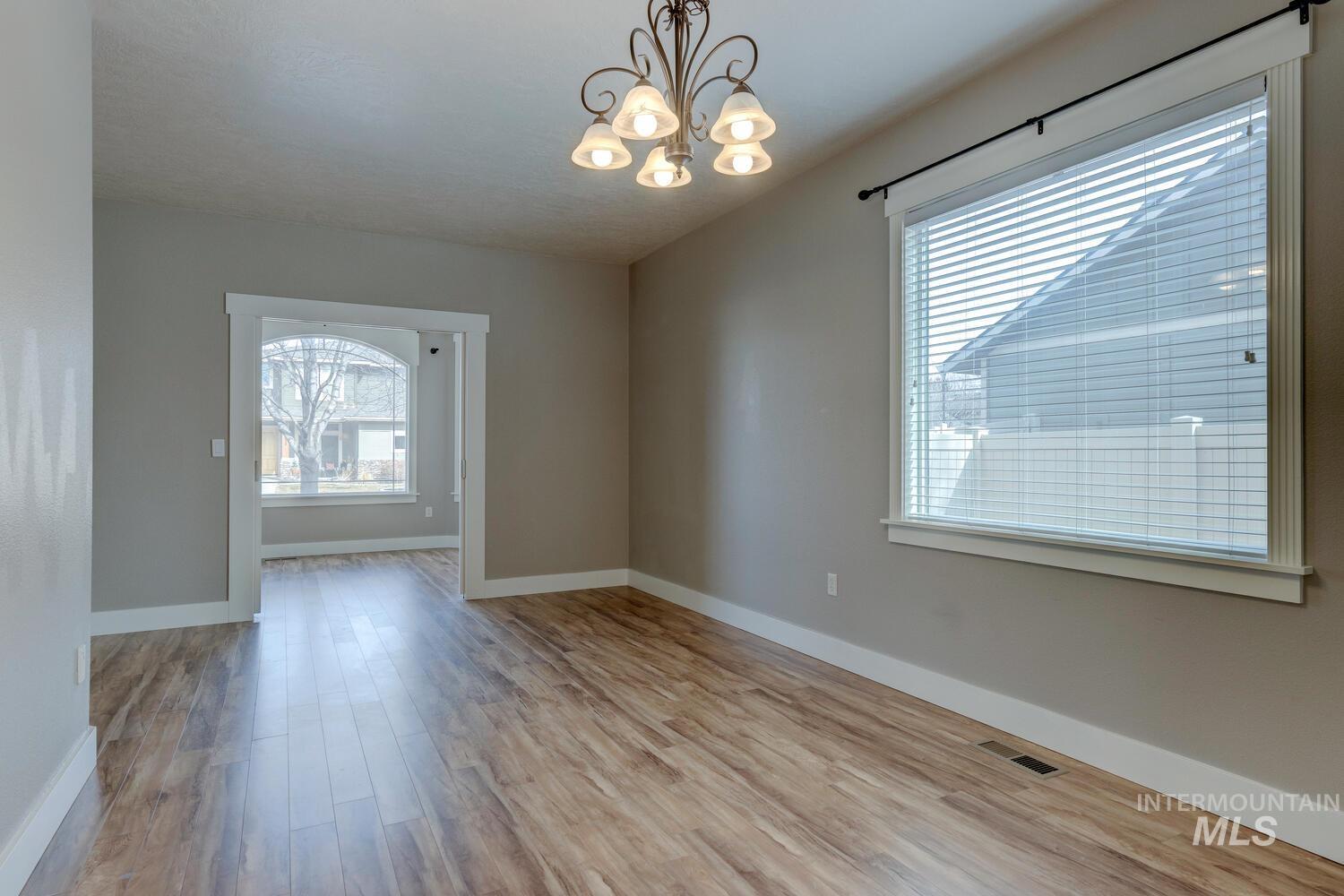 Unfurnished dining area with a chandelier, light wood-style flooring, and plenty of natural light
