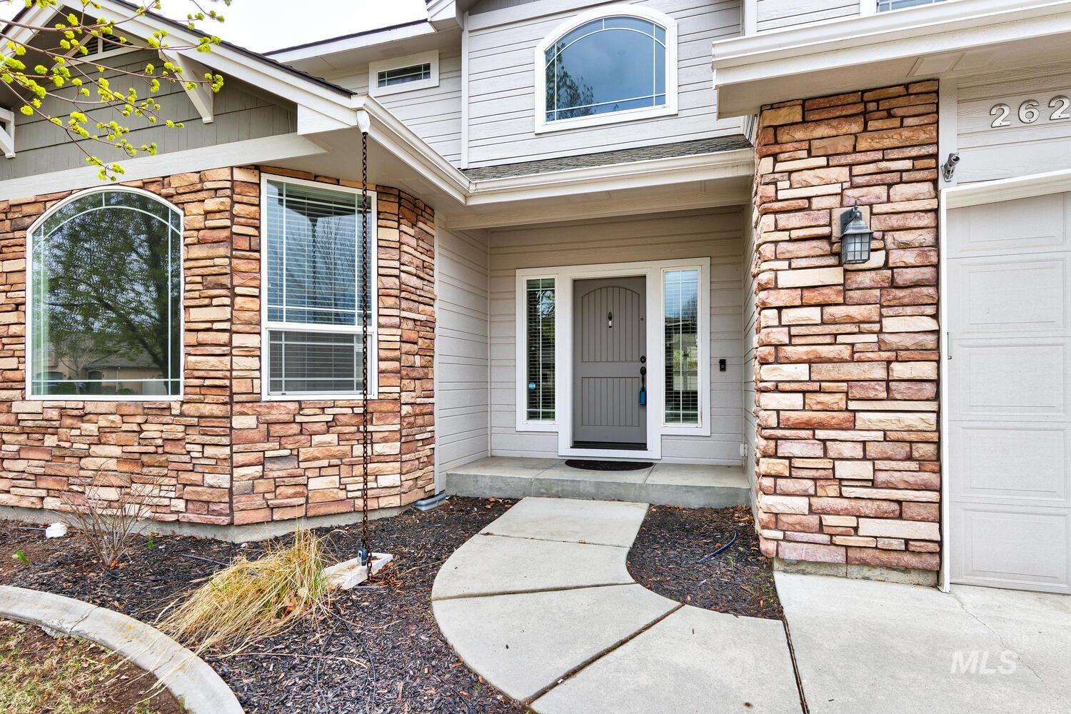 View of exterior entry with stone siding, covered porch, and a garage