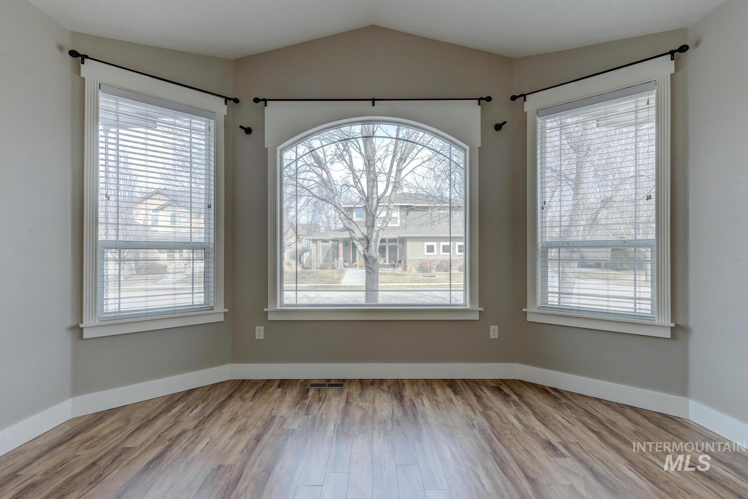 Unfurnished dining area with light wood finished floors and vaulted ceiling