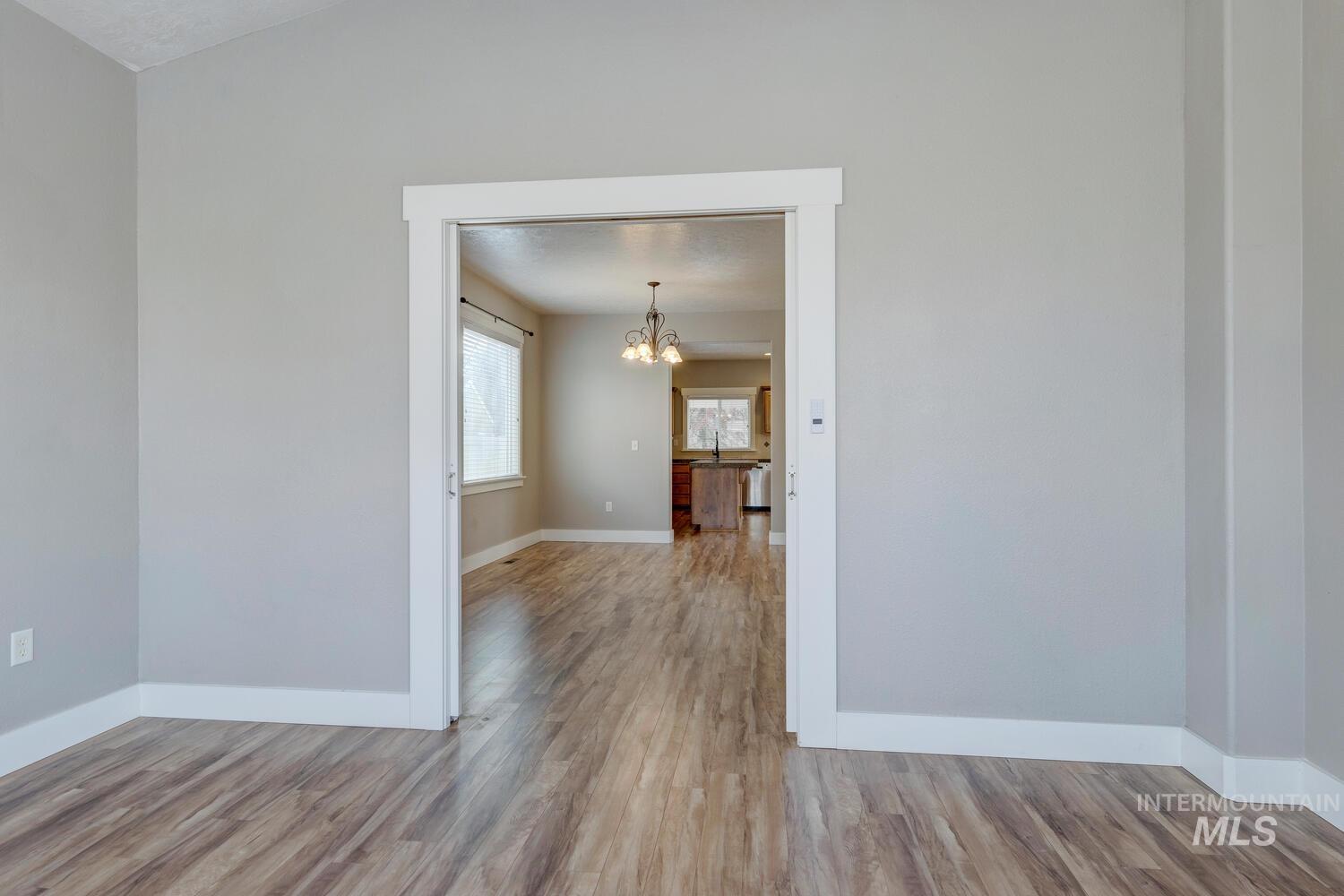 Unfurnished room featuring light wood finished floors and a chandelier