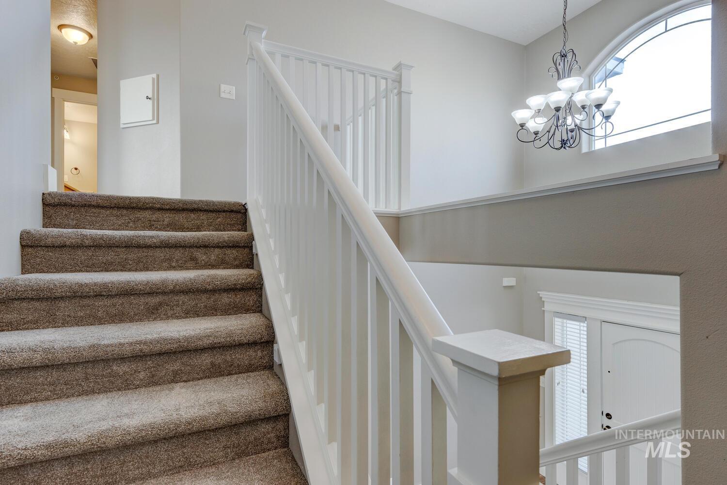 Staircase featuring a chandelier