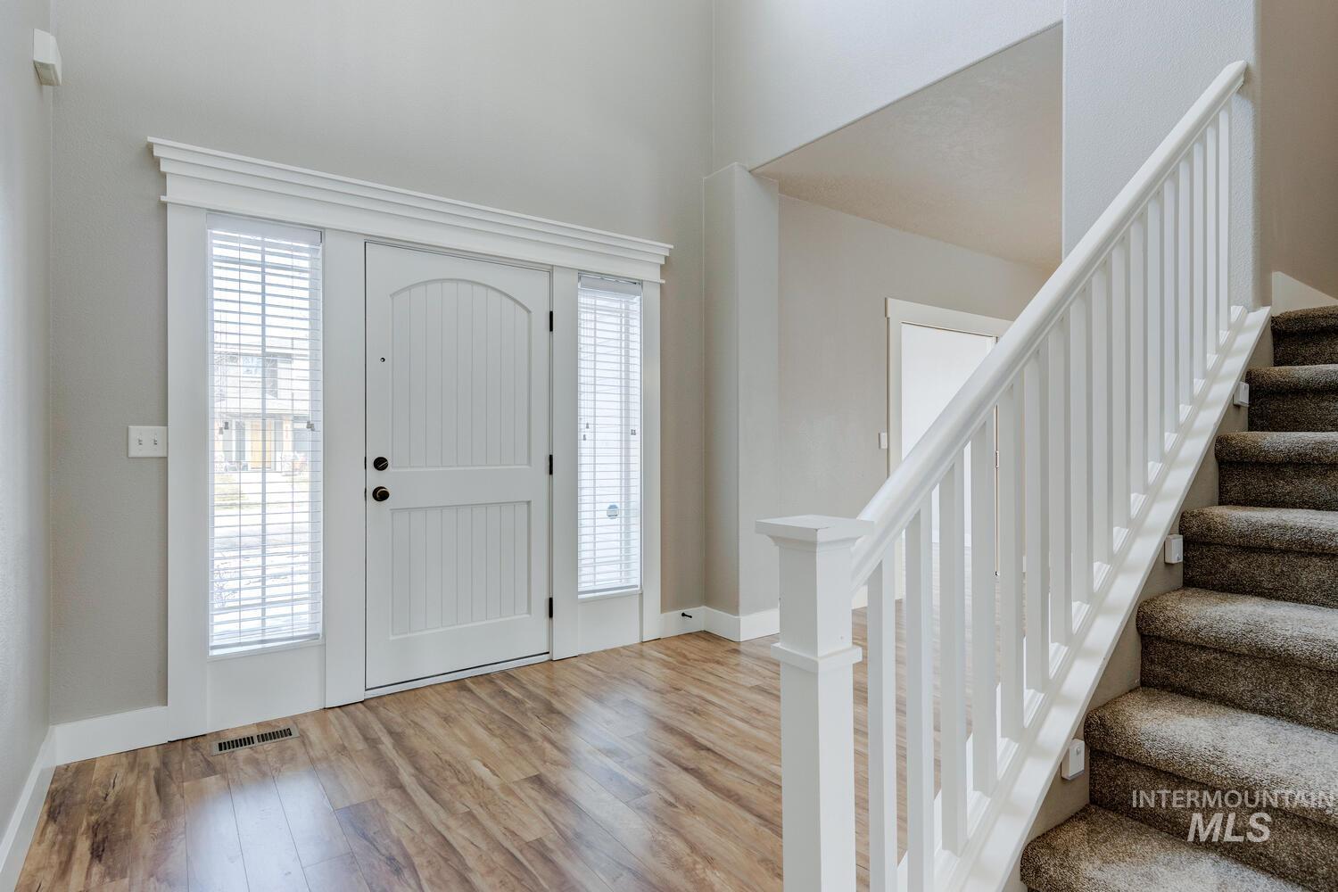 Foyer entrance featuring stairs, light wood finished floors, and a high ceiling