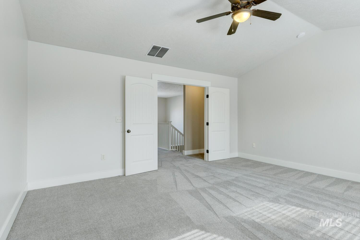 Unfurnished room featuring carpet, lofted ceiling, and a ceiling fan