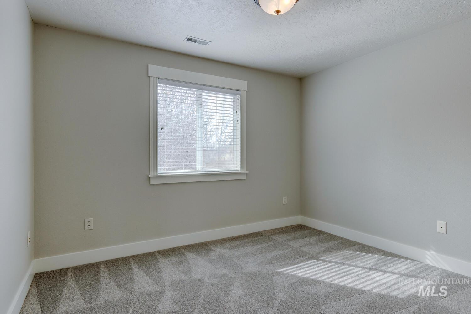 Carpeted spare room featuring baseboards and a textured ceiling