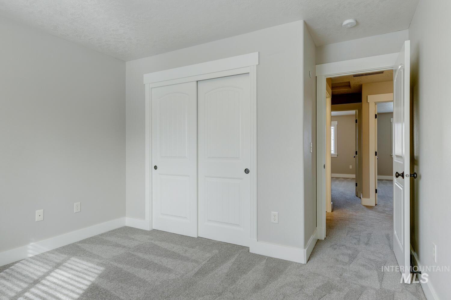 Unfurnished bedroom with light carpet, a closet, and a textured ceiling