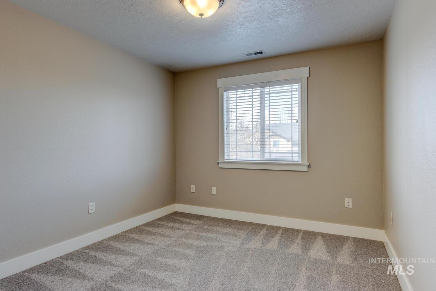 Unfurnished room featuring light colored carpet and a textured ceiling