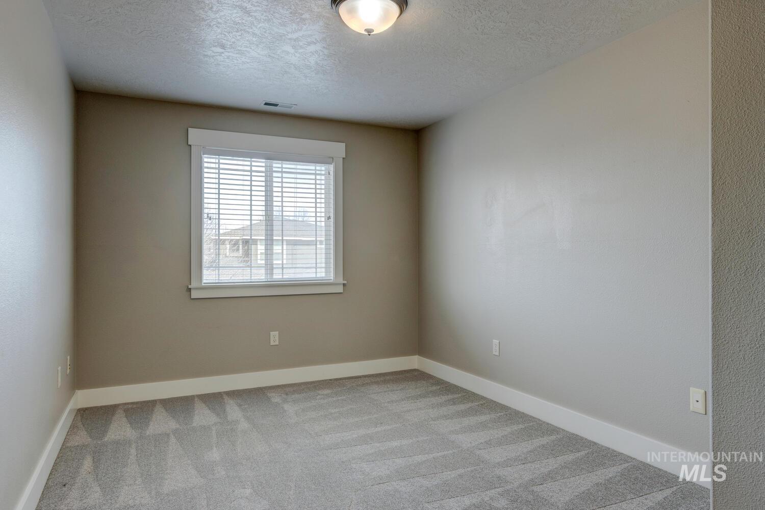 Unfurnished room featuring light colored carpet and a textured ceiling