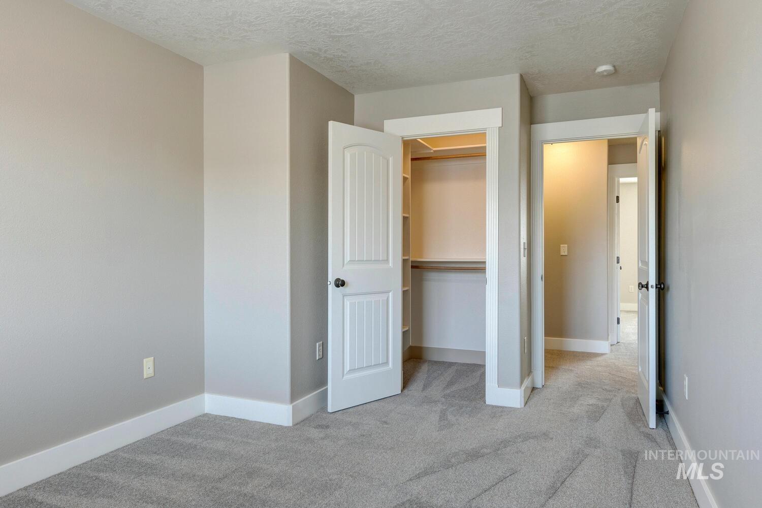 Unfurnished bedroom featuring light colored carpet, a textured ceiling, and a closet