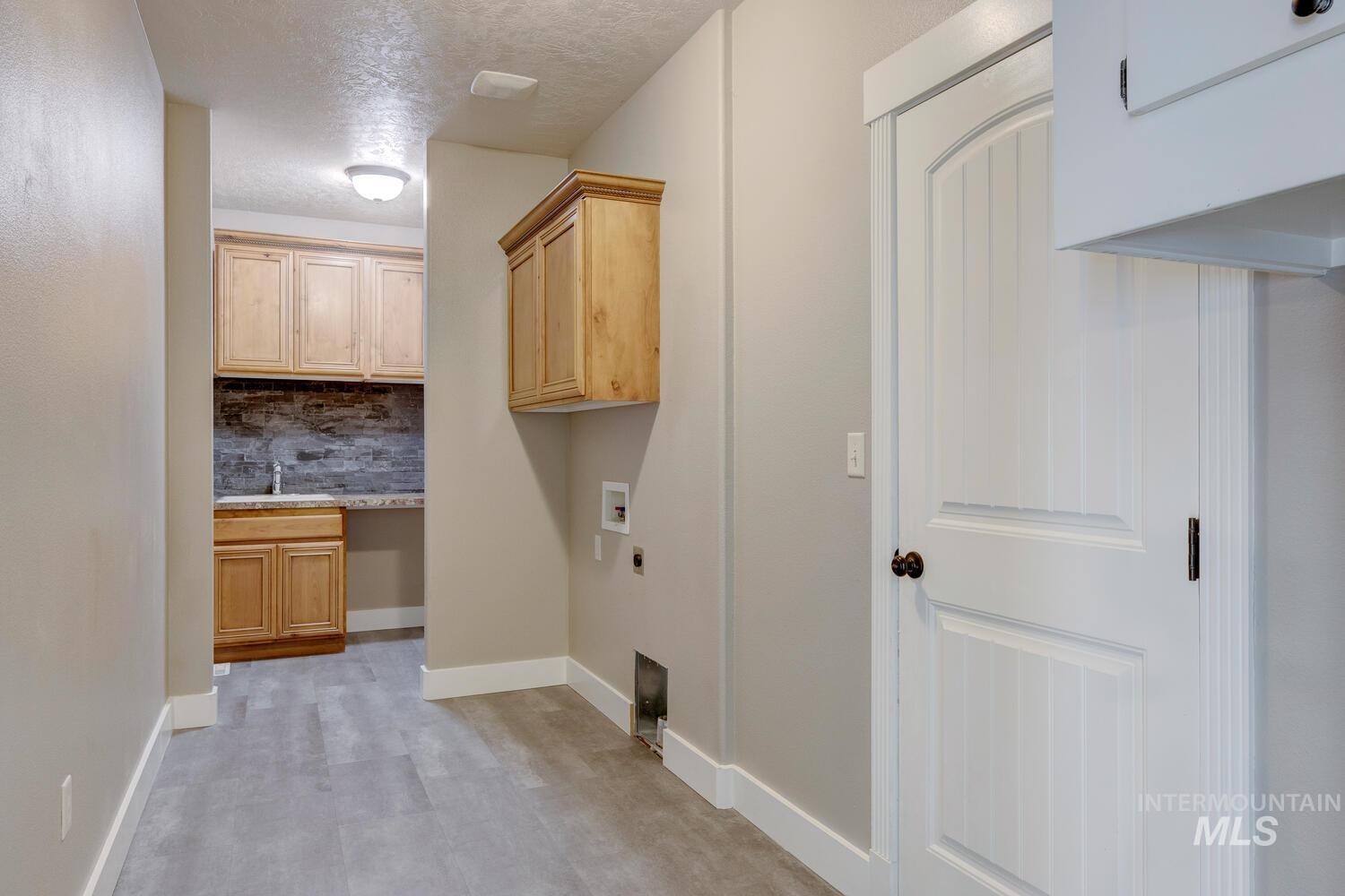 Washroom with cabinet space, a textured ceiling, electric dryer hookup, and hookup for a washing machine