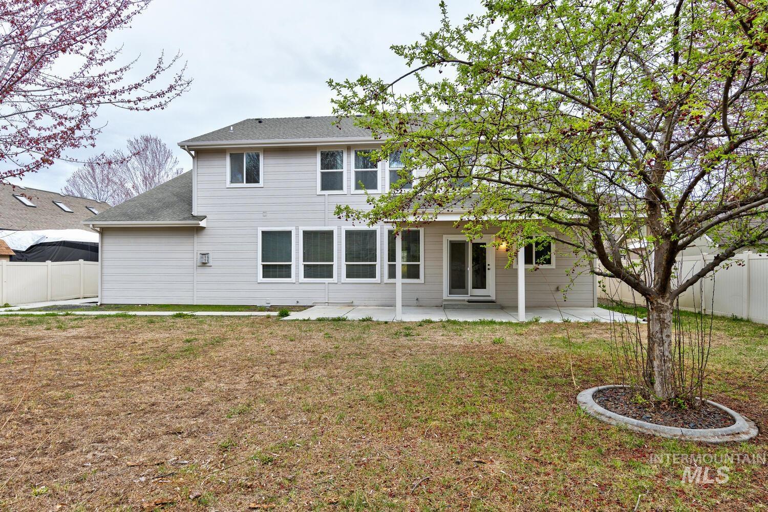 Back of house featuring a patio area and roof with shingles