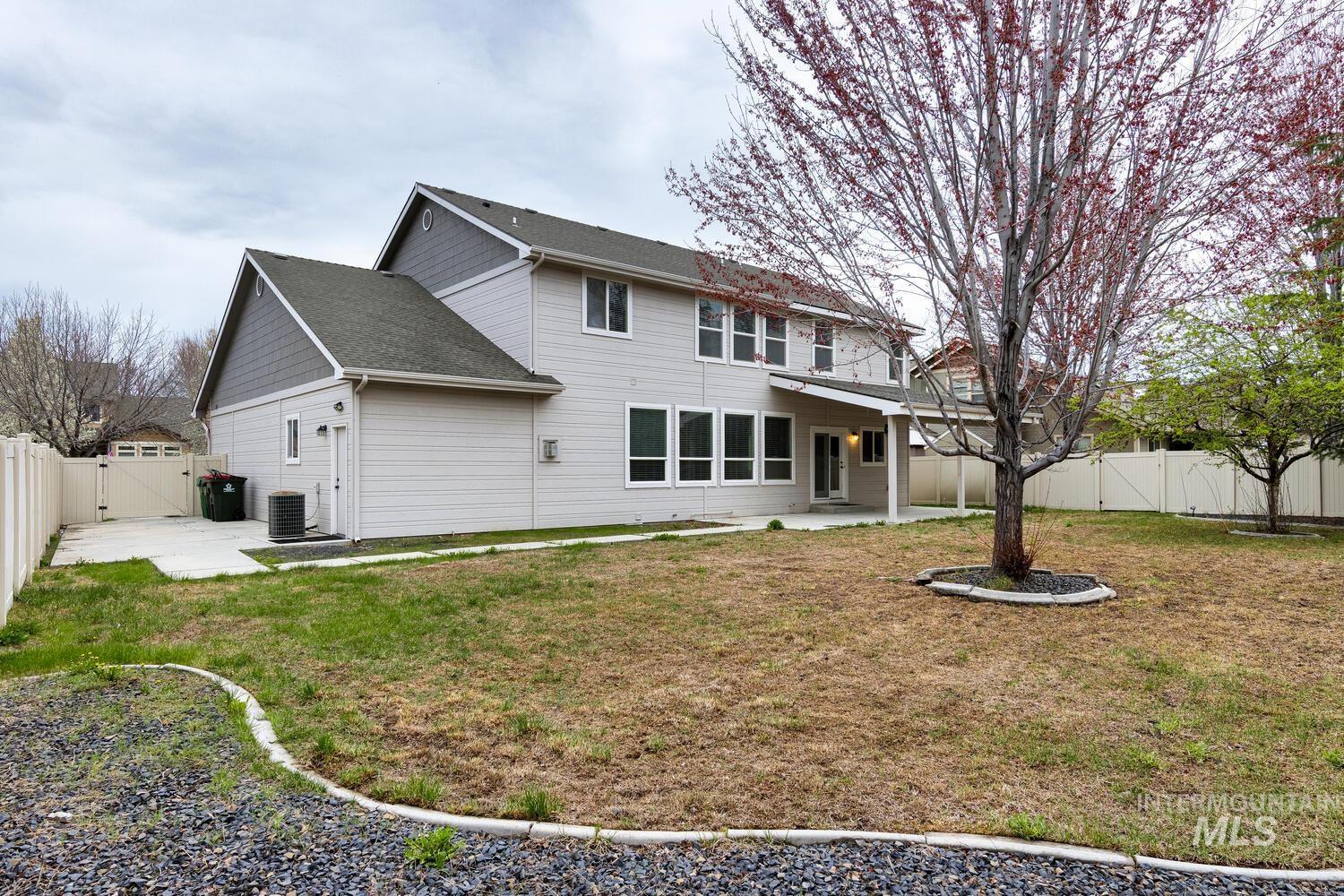 Rear view of house featuring a fenced backyard, a patio, a gate, and a shingled roof