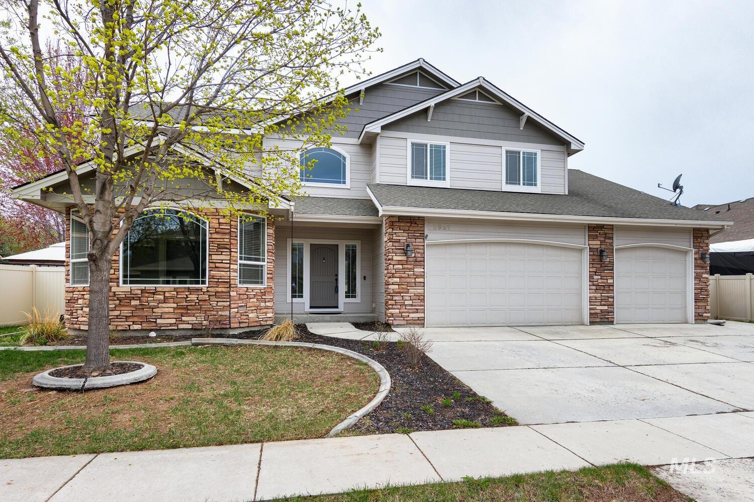 View of front of property featuring stone siding, driveway, and roof with shingles