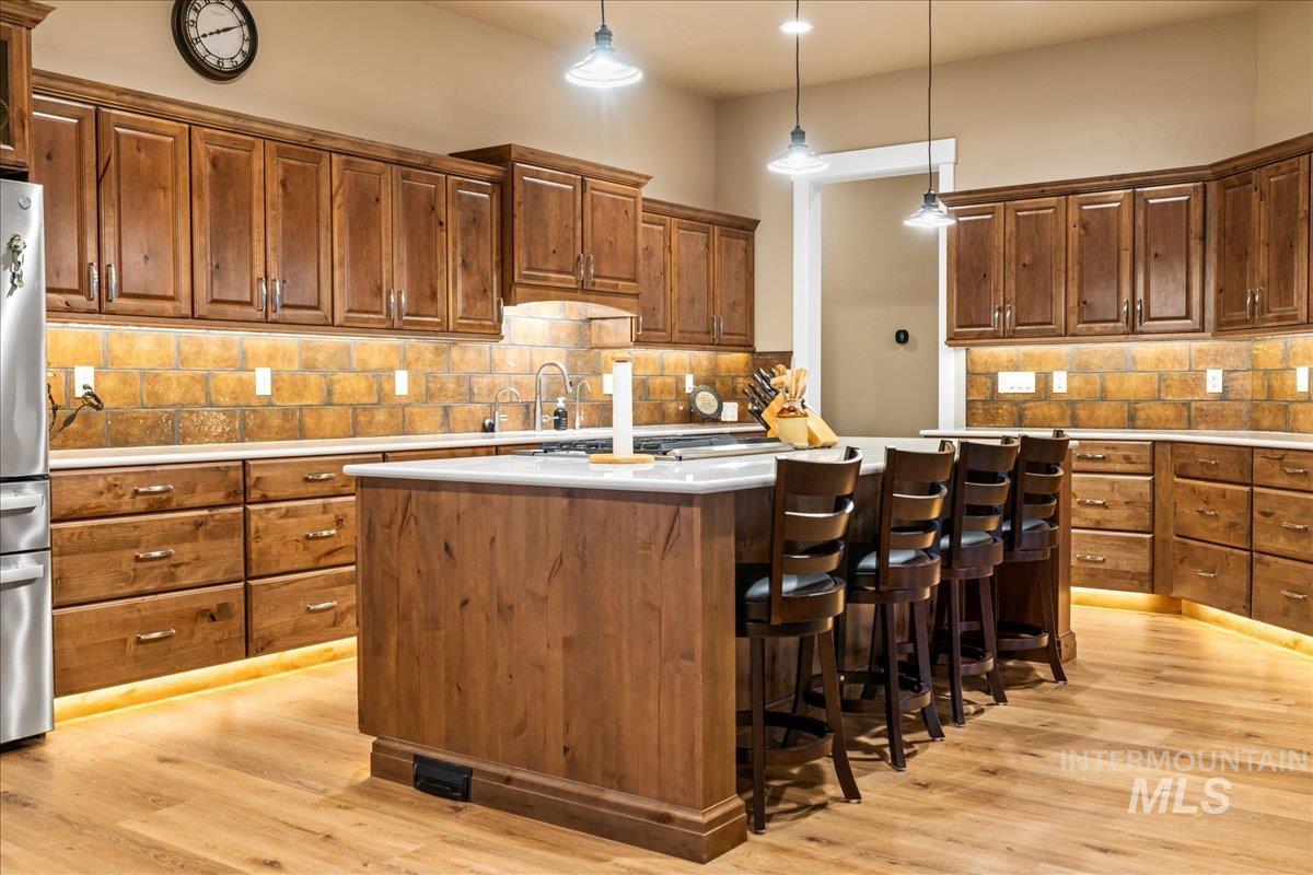 Kitchen featuring a center island, pendant lighting, tasteful backsplash, and light wood finished floors