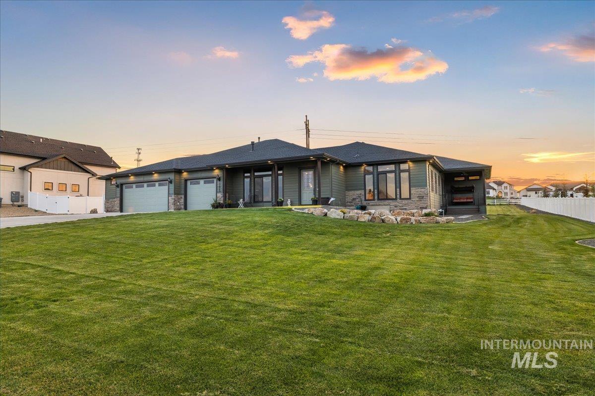 Prairie-style home featuring stone siding, a garage, a patio area, and driveway