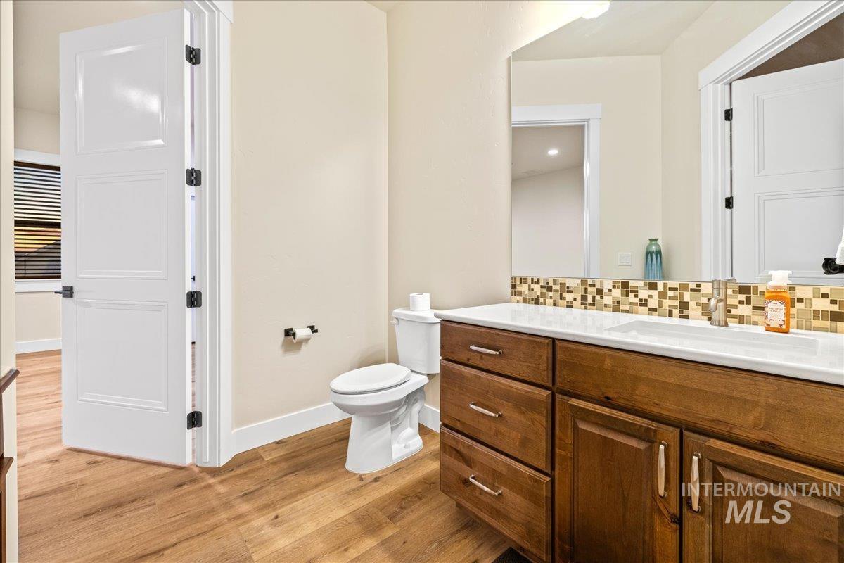Bathroom with vanity, light wood-type flooring, and backsplash